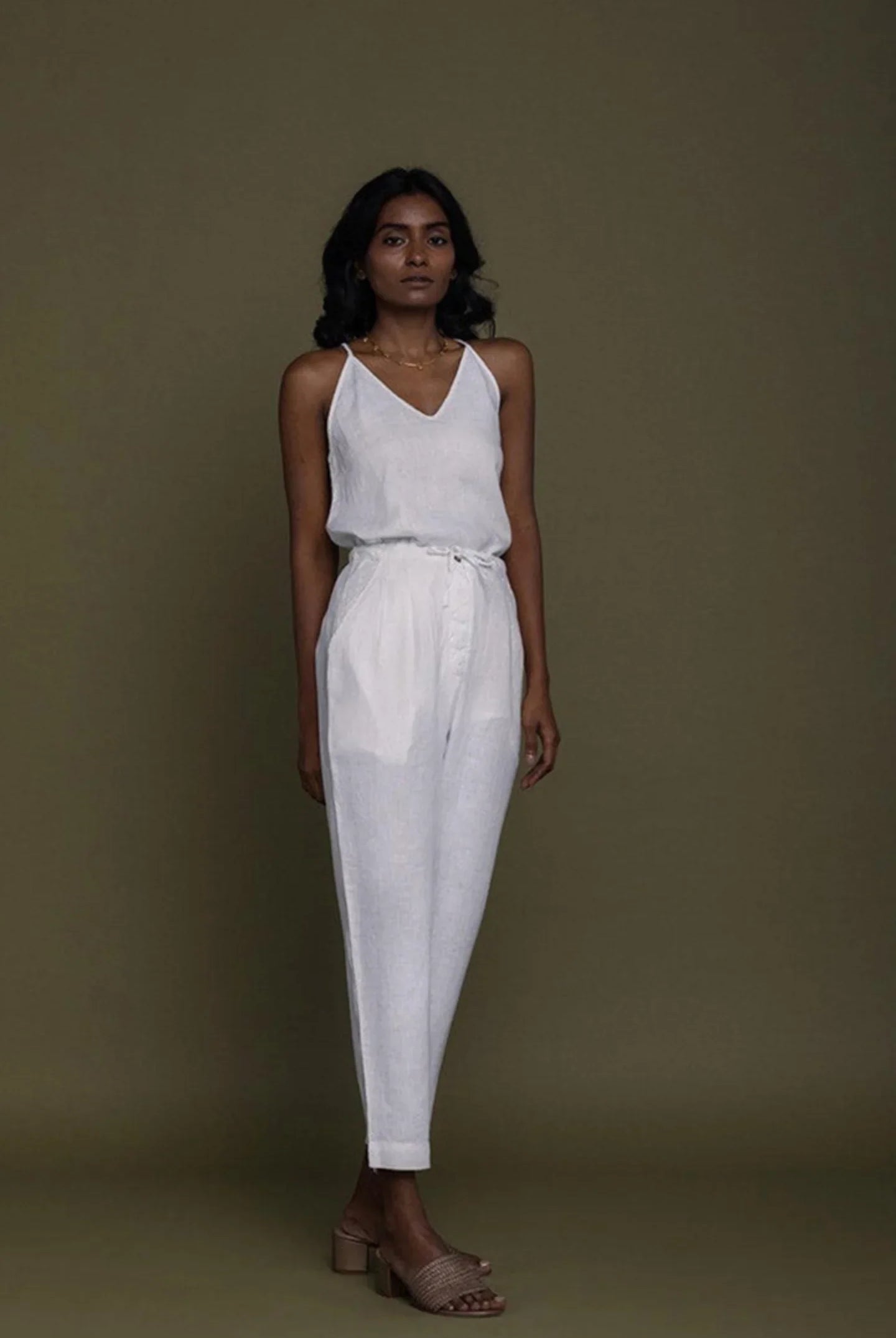 Reistor white sleeveless V-neck top with tapered pants and tie-waist detail, sustainable women's fashion look.