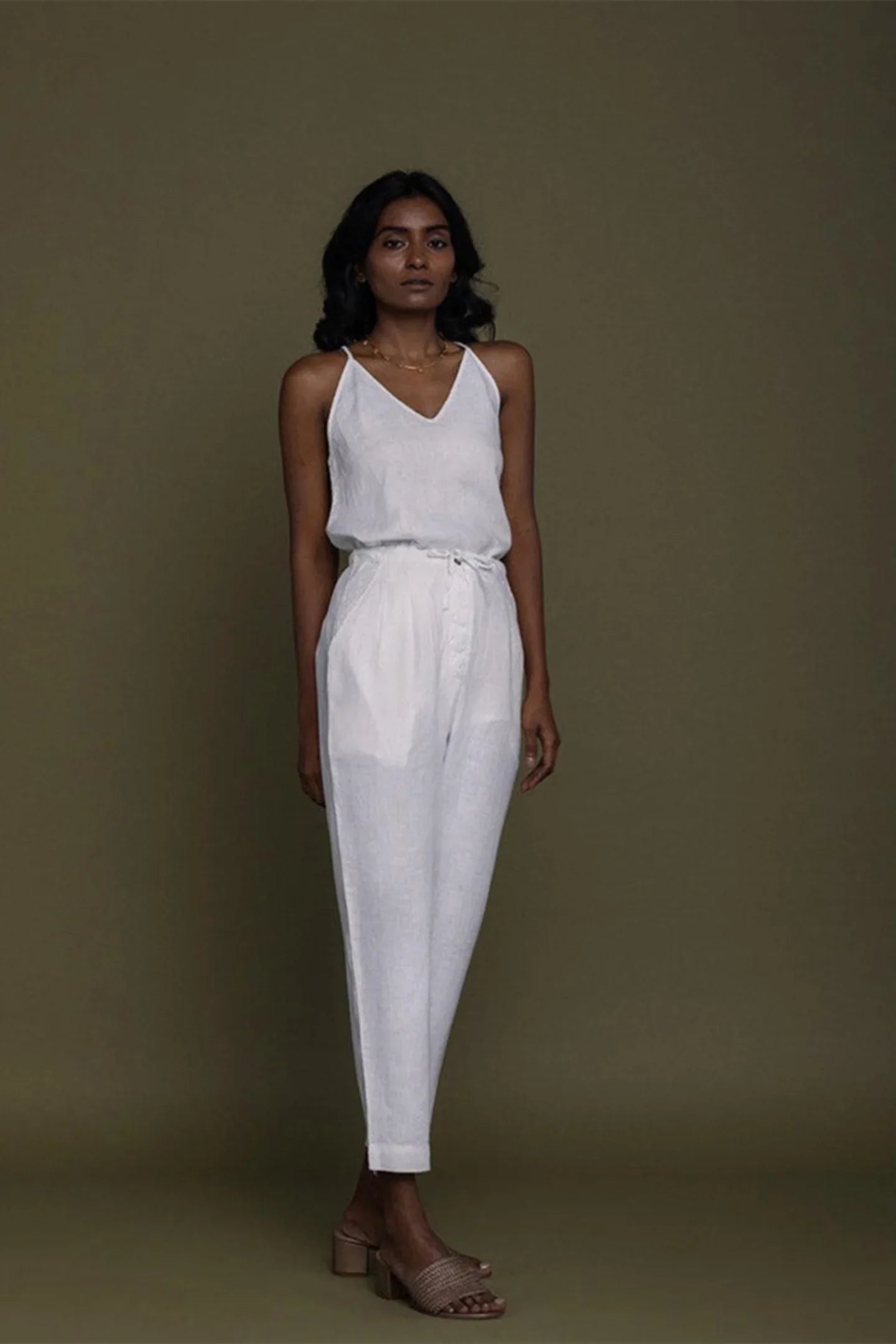 Reistor white sleeveless V-neck top with tapered pants and tie-waist detail, sustainable women's fashion look.