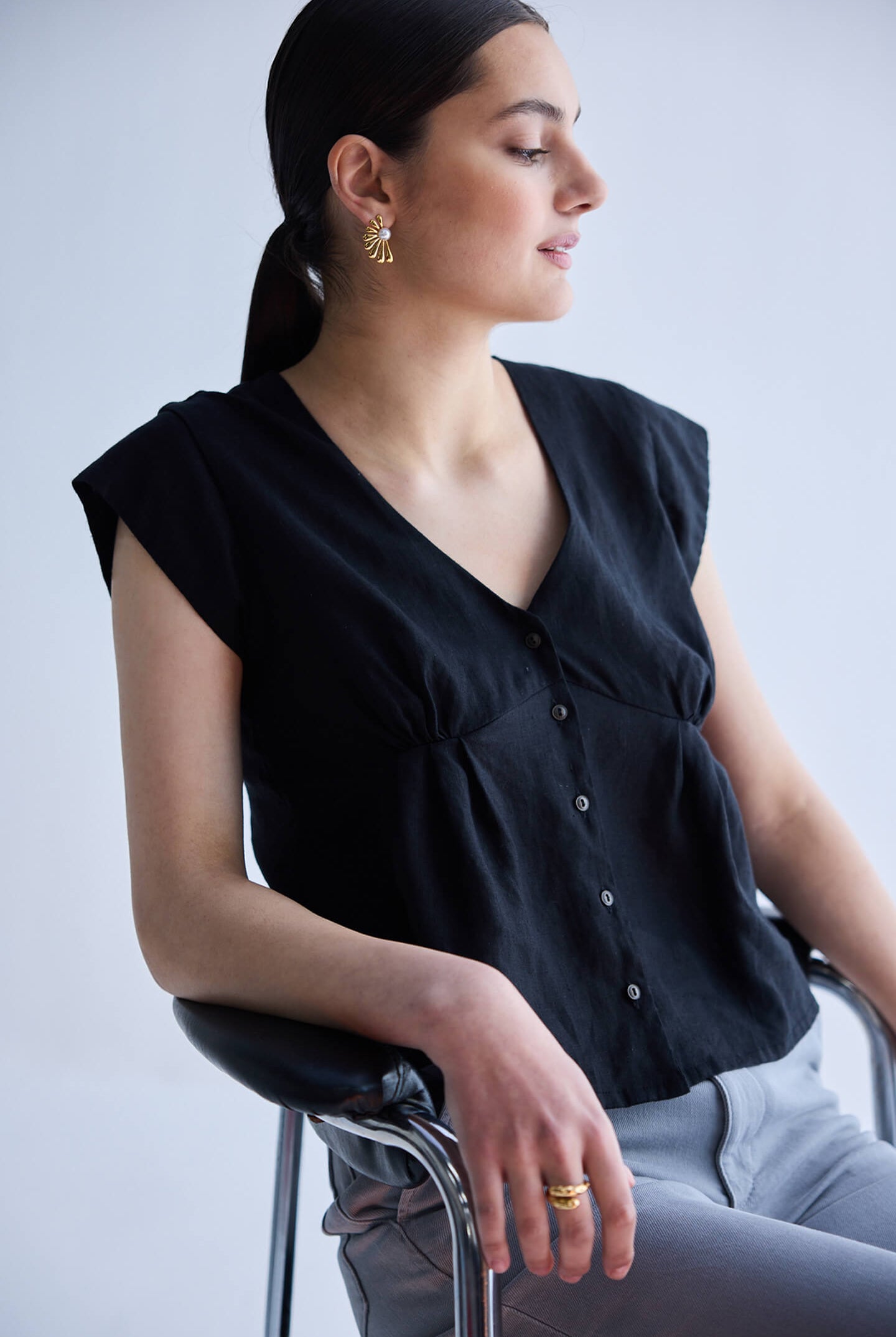 Deep V-neck short top in Black by reistor featuring cap sleeves, front button detailing, and breathable lightweight fabric in a relaxed fit design.