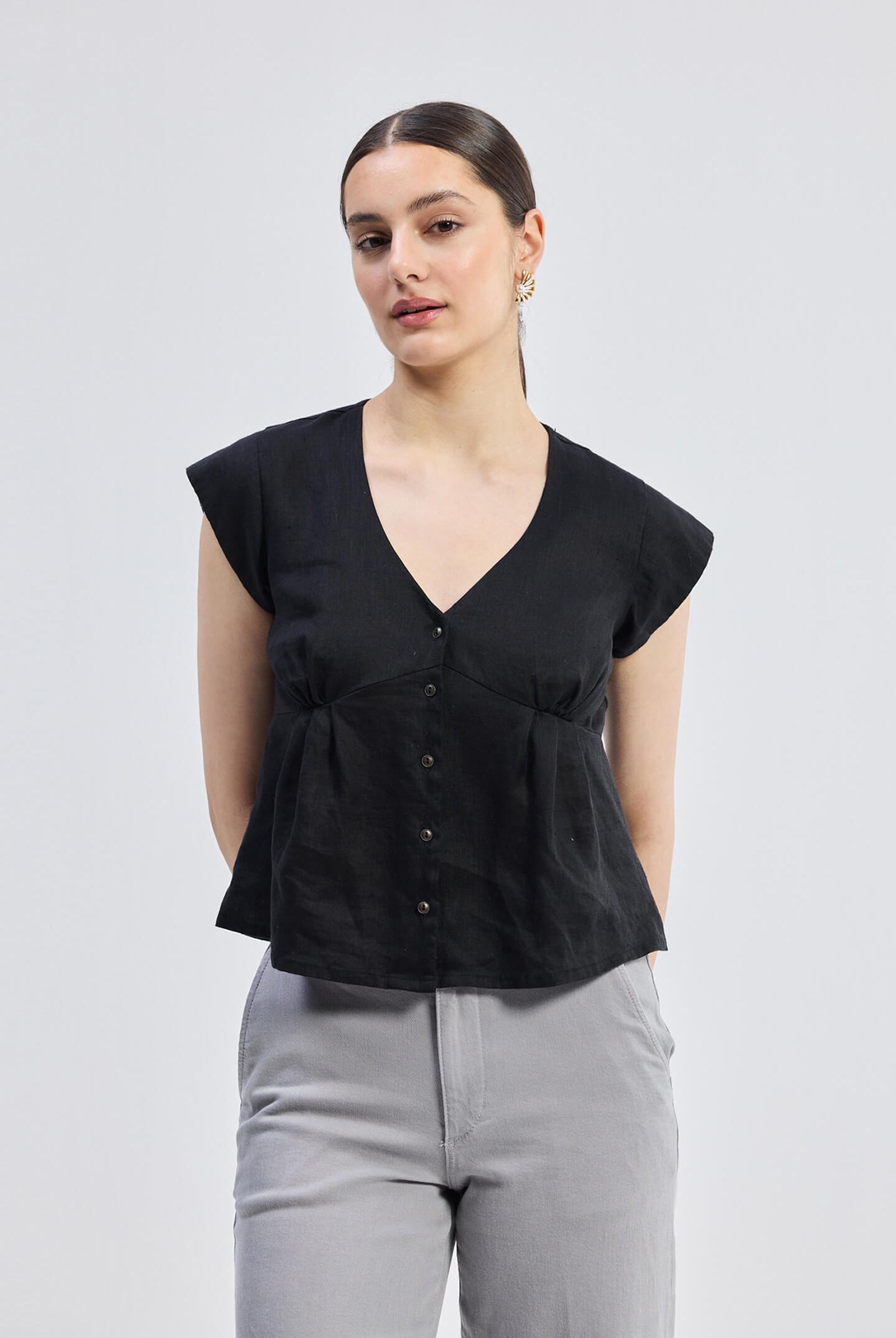 Deep V-neck short top in Black by reistor with cap sleeves, front button closure, and breathable linen fabric in a relaxed fit silhouette for everyday wear.