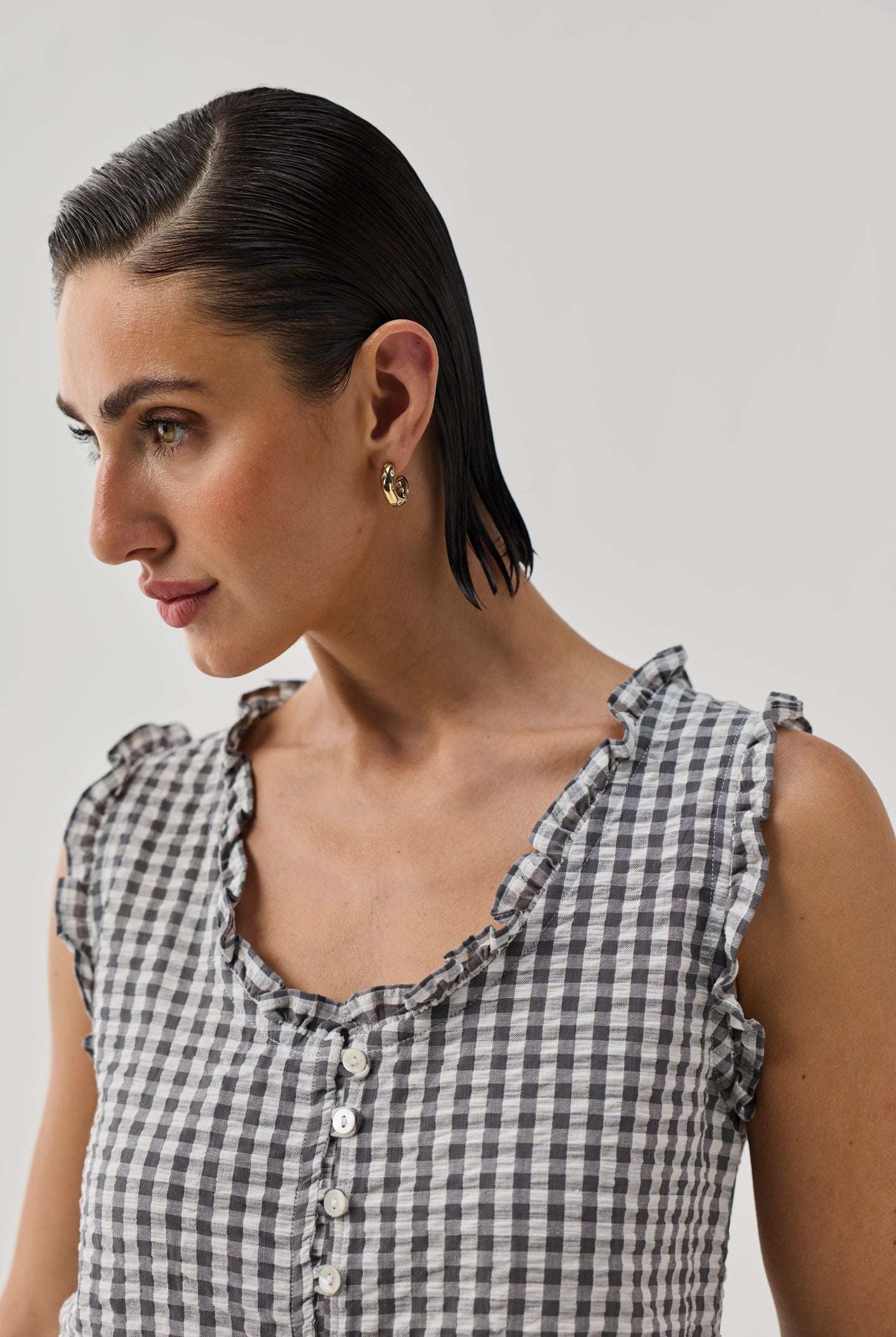 Close-up of Embroidered Peplum Top in Grey Check by Reistor with ruffle neckline