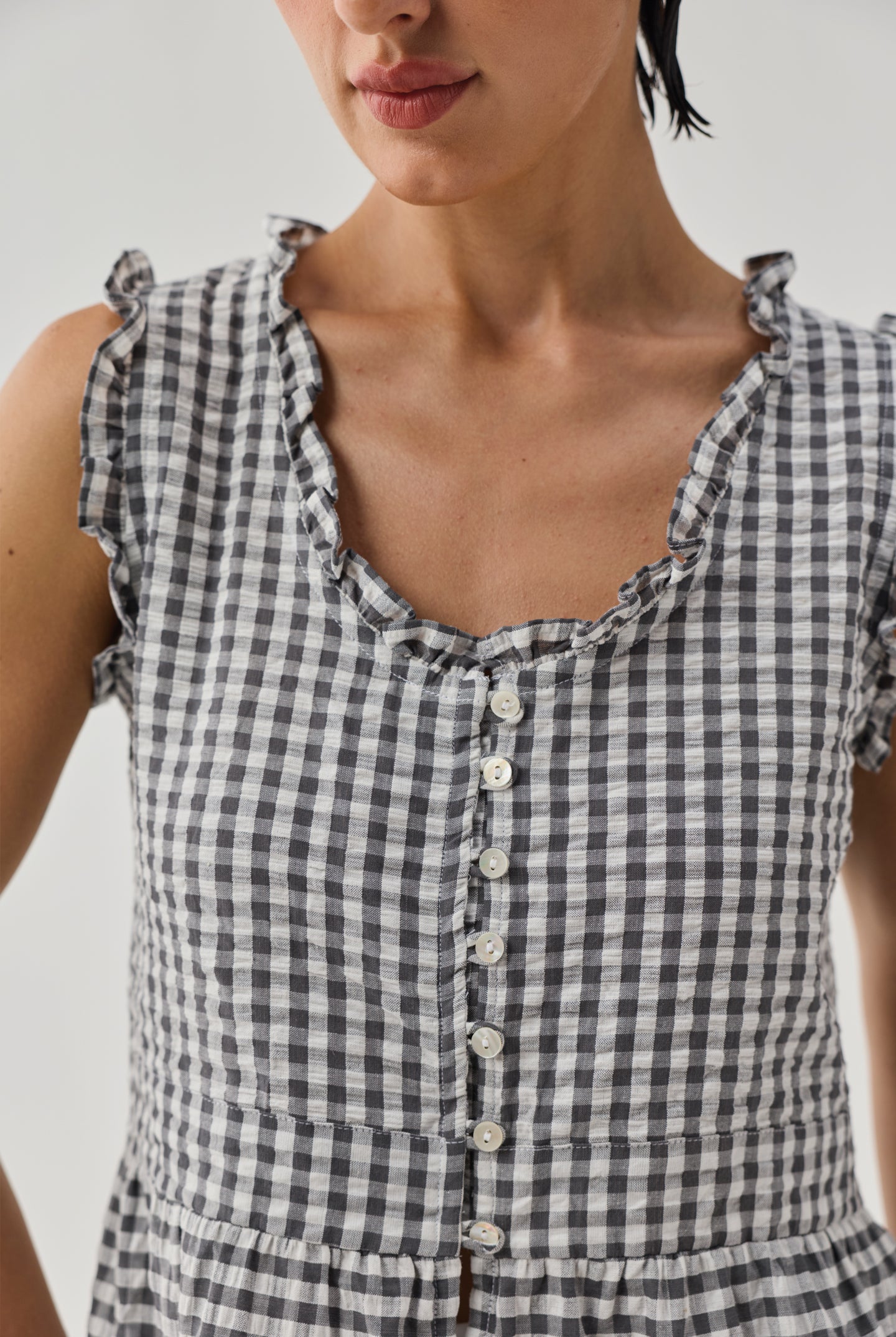 Detailed view of grey check embroidered peplum top with textured fabric