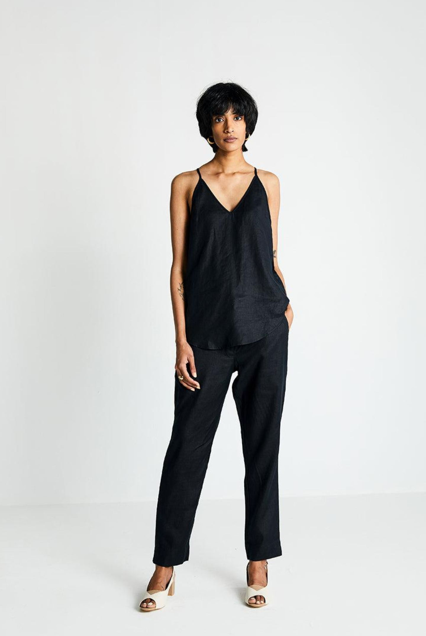 Woman wearing the Reistor Endless Sunday Top in Black, a sleeveless sustainable top paired with black pants, featuring a relaxed fit for effortless everyday style.