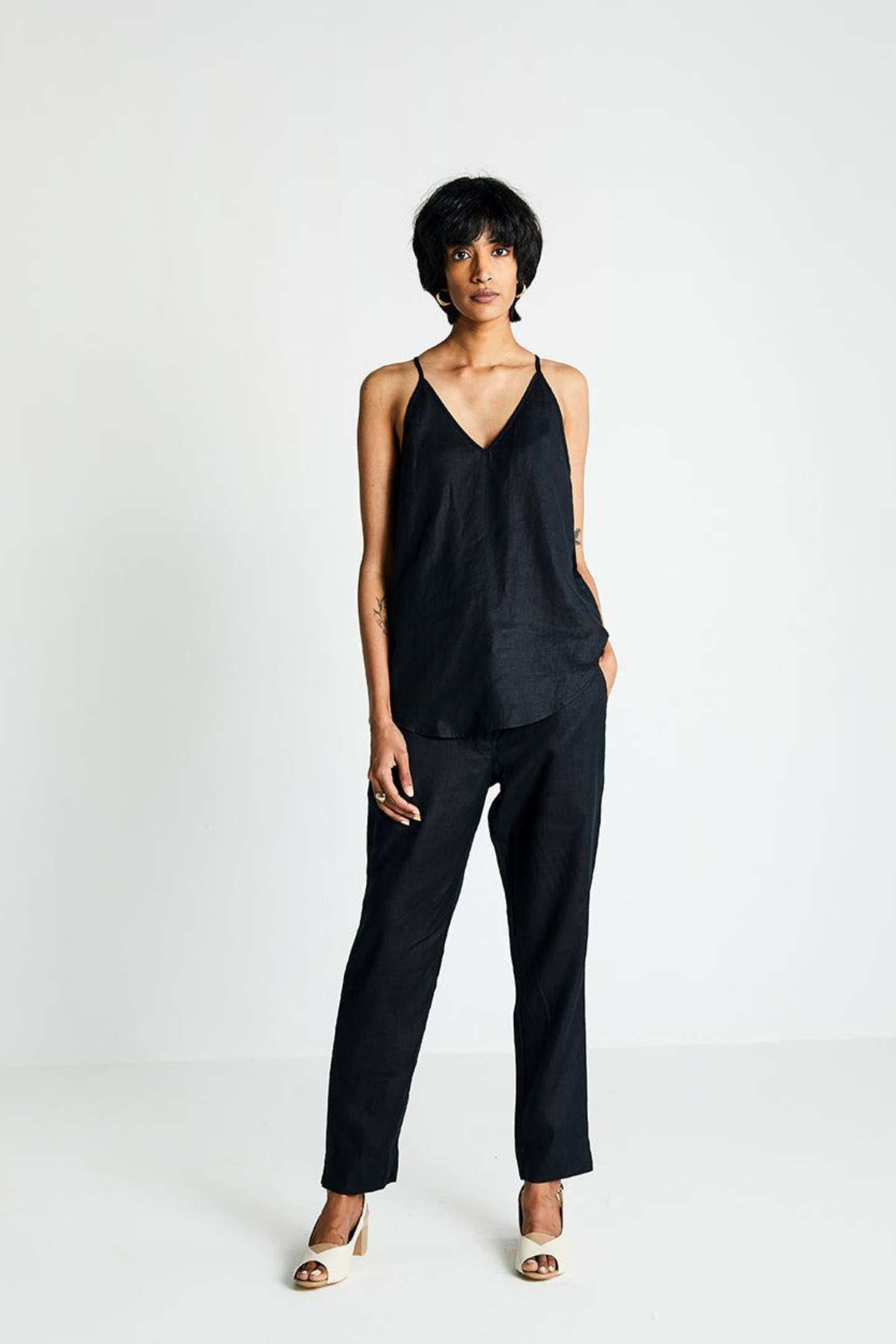Woman wearing the Reistor Endless Sunday Top in Black, a sleeveless sustainable top paired with black pants, featuring a relaxed fit for effortless everyday style.
