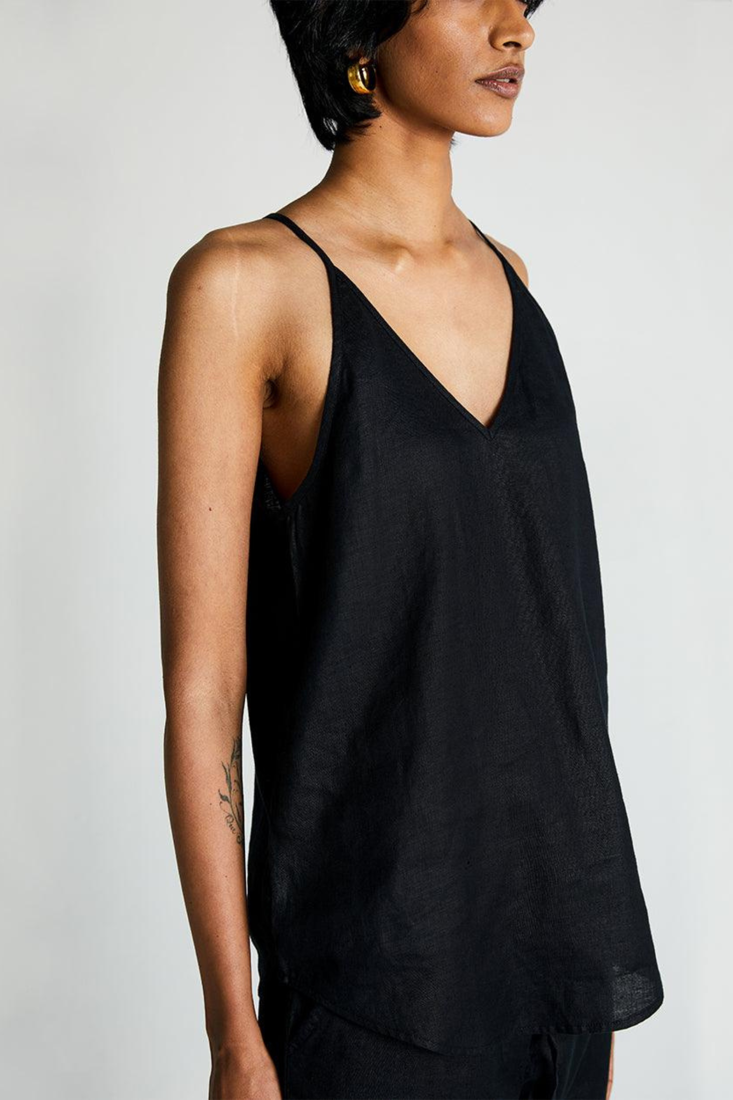 Woman wearing the Reistor Endless Sunday Top in Black, a sleeveless sustainable women's top with a relaxed fit, perfect for everyday wear and effortless styling.