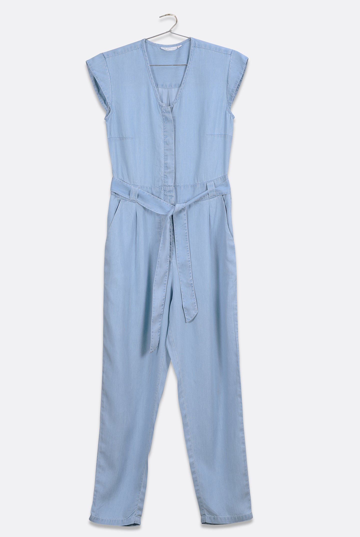 Reistor Evening Chai Jumpsuit in Blue Denim, sleeveless V-neck one-piece with cap sleeves, adjustable tie belt, tapered legs, and sustainable fabric.