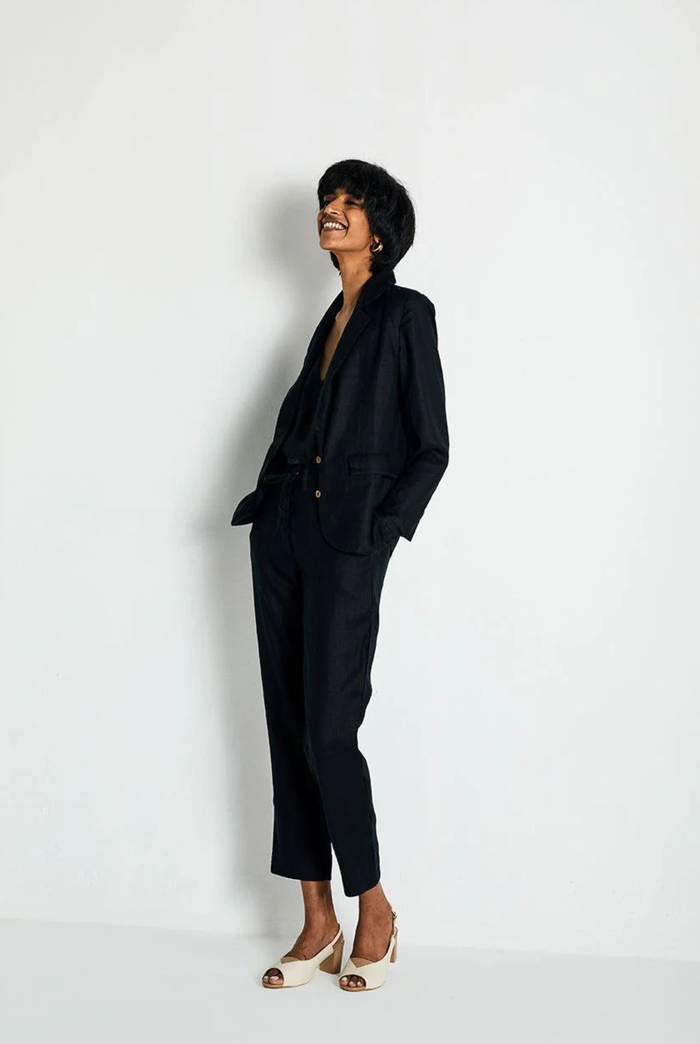Person wearing a black suit standing against a white background