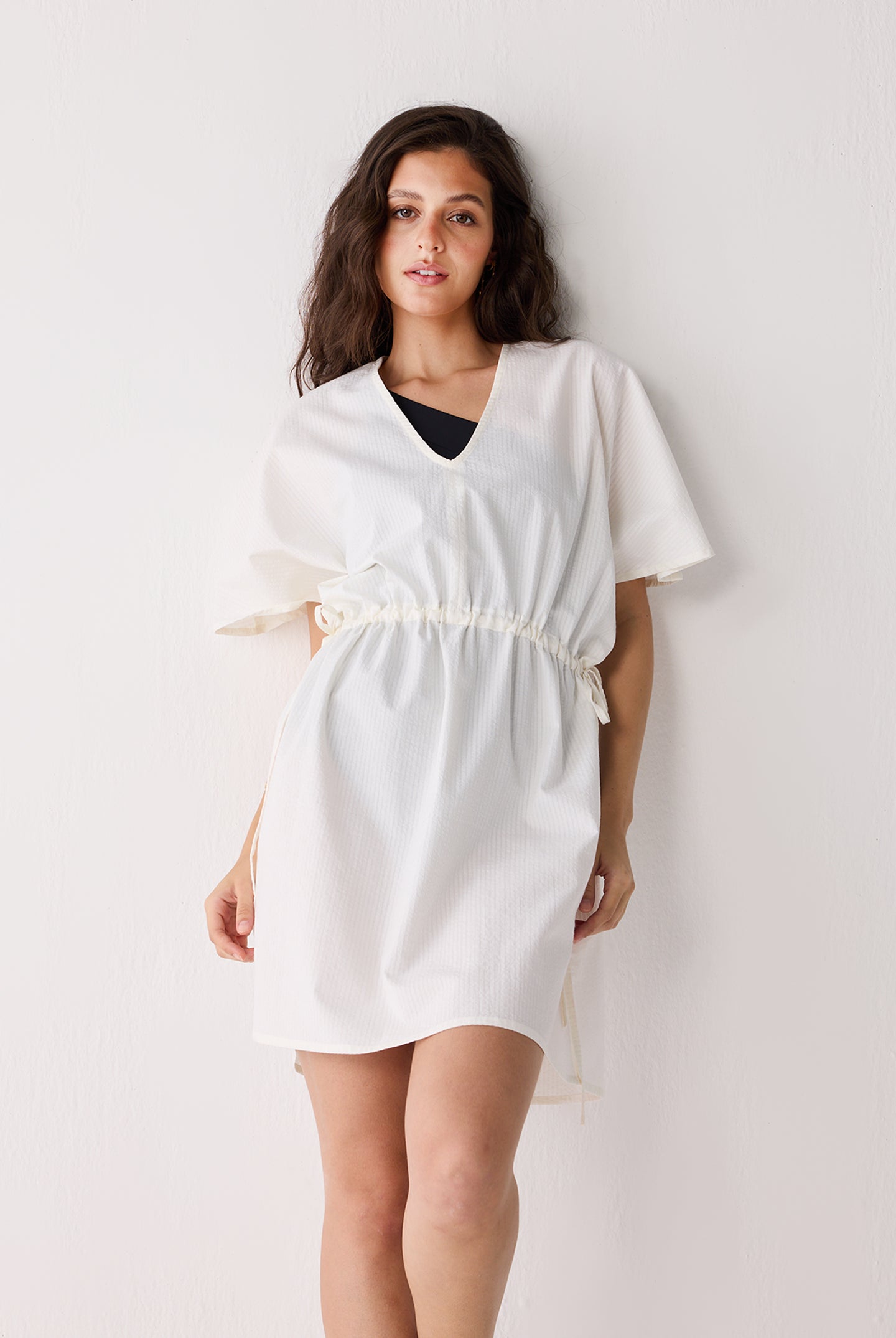 Woman wearing a white dress against a plain background