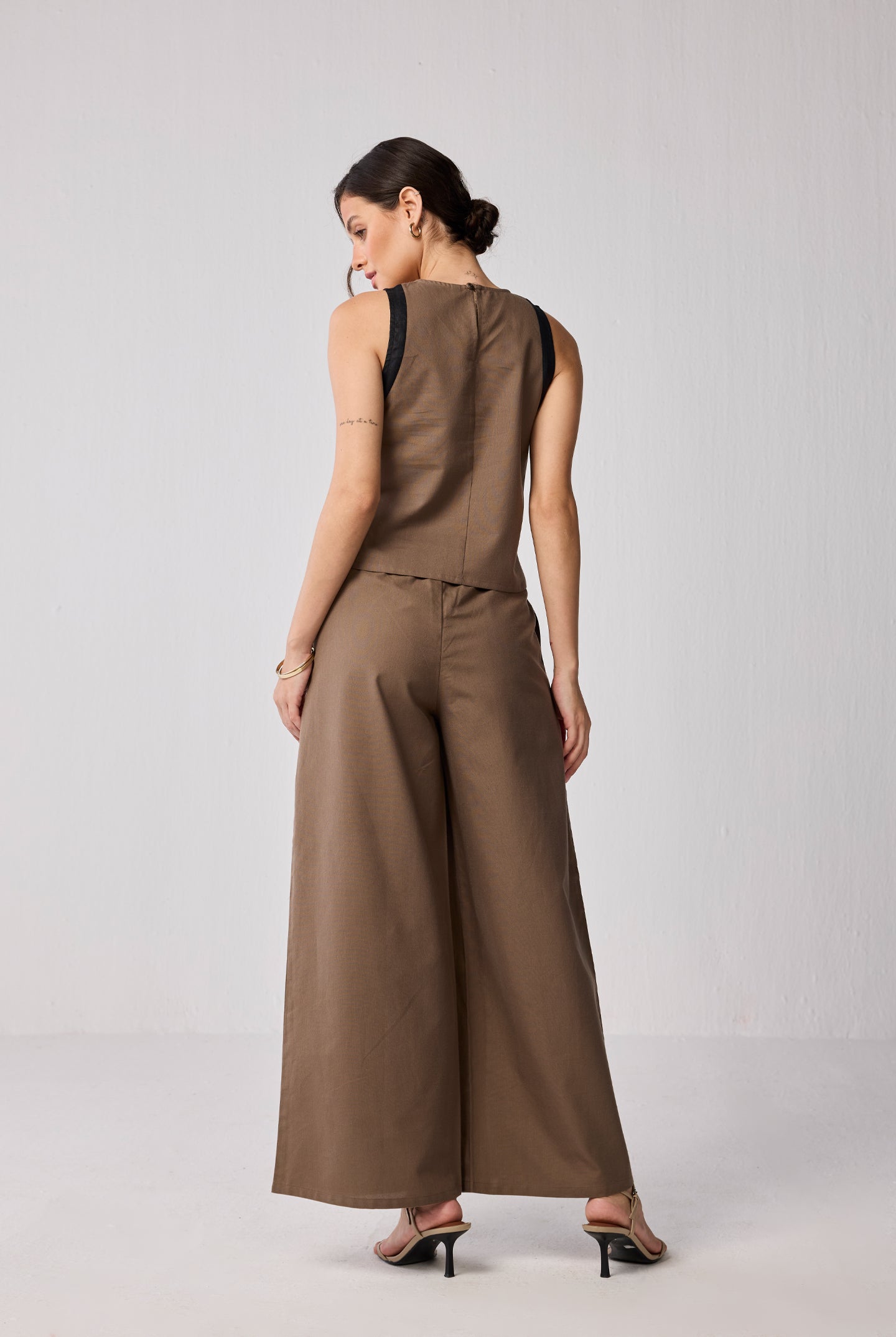 Rear view of a woman wearing a matching brown set featuring wide-leg pants and a colorblock sleeveless top.