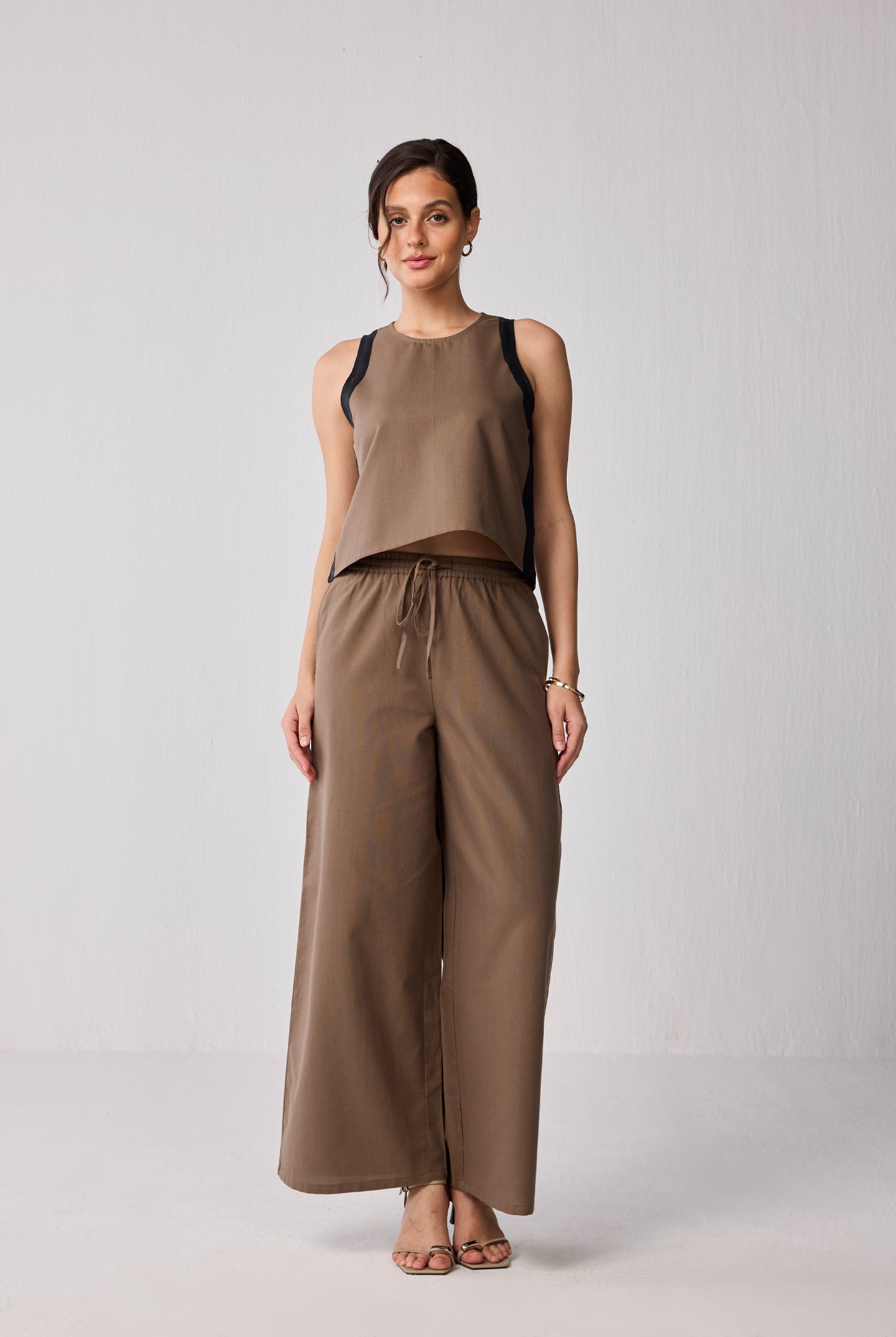 Model wearing a Reistor sustainable Matching Set featuring wide-leg drawstring pants and a colorblock top in brown, crafted from eco-friendly fabric.
