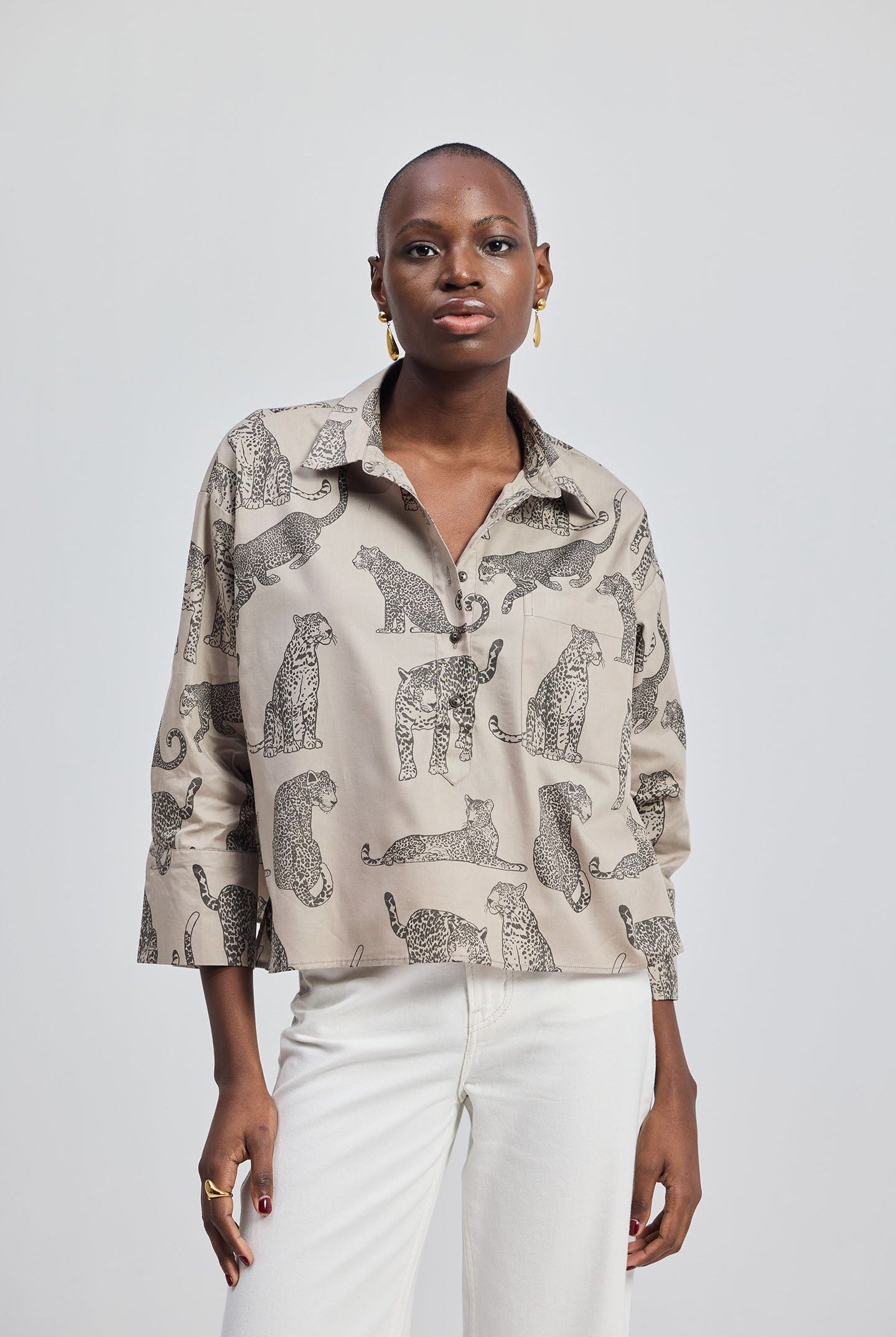 Woman wearing a patterned shirt with animal designs by reistor on a plain background.