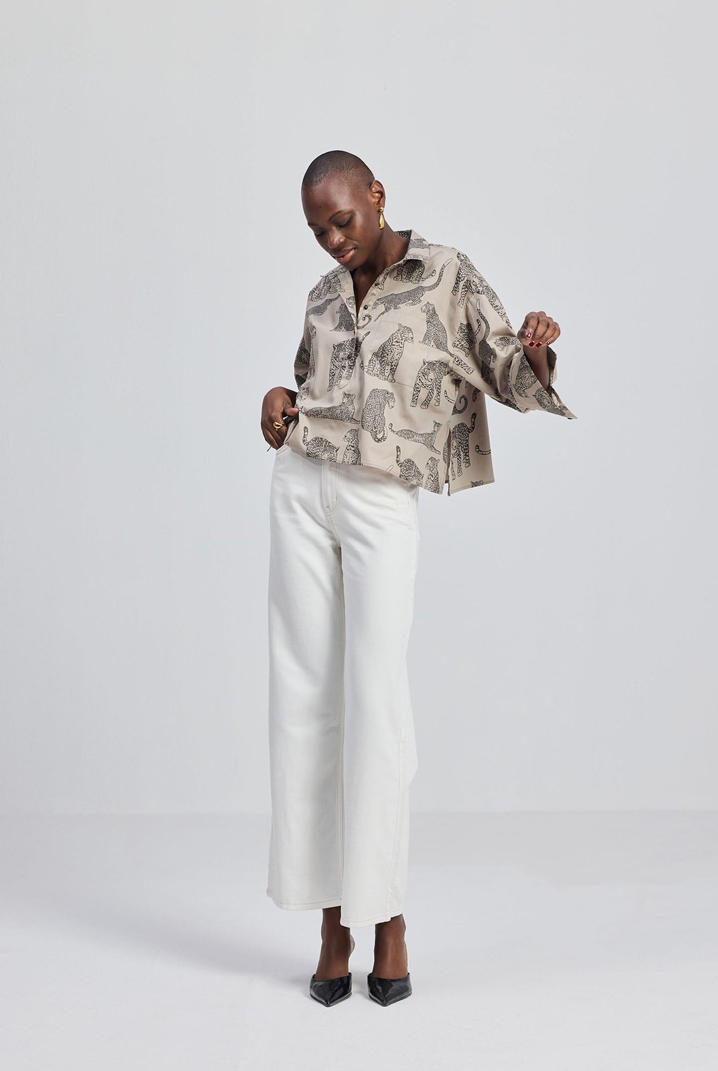 Model wearing a Reistor Oversized Cropped Button-down Shirt In Animal Print paired with white wide-leg trousers and black pointed heels.