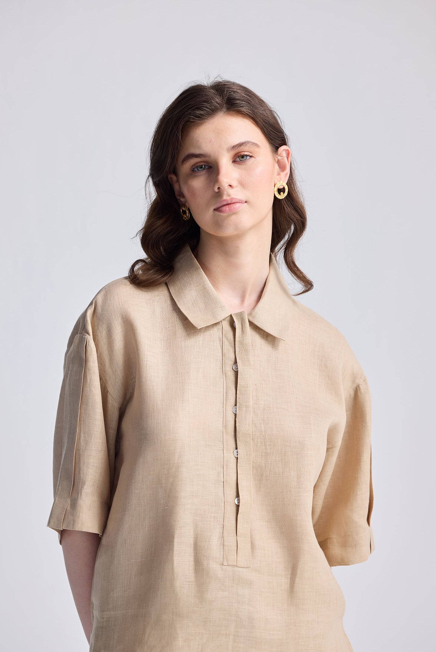 Woman wearing an Oversized Flowy Shirt in Neutral Beige, featuring a relaxed linen-look fabric, short sleeves, and a half-button placket.