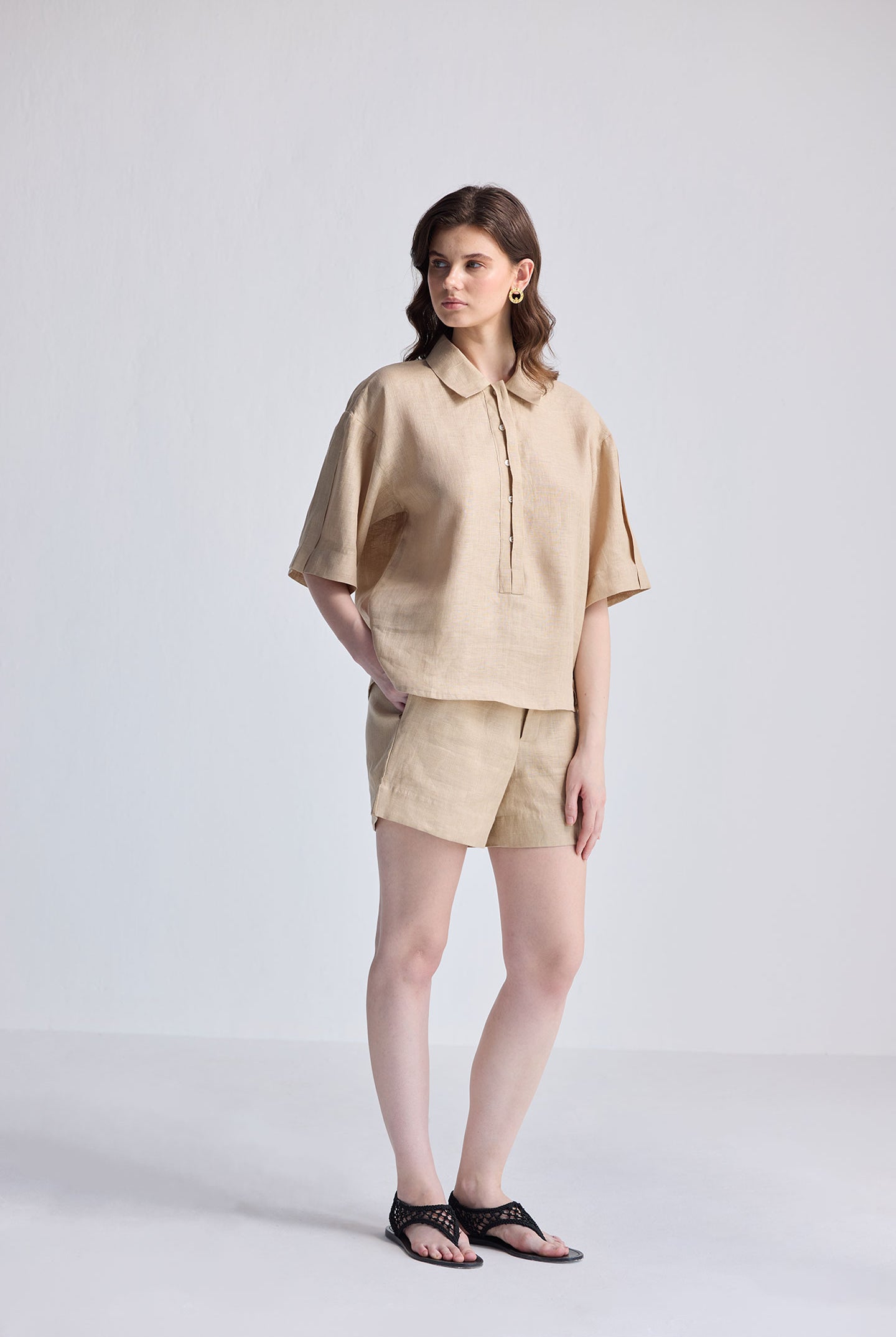 Model wearing an Oversized Flowy Shirt in Neutral Beige, featuring a textured linen fabric, relaxed short sleeves, and a half-button placket with a classic collar.
