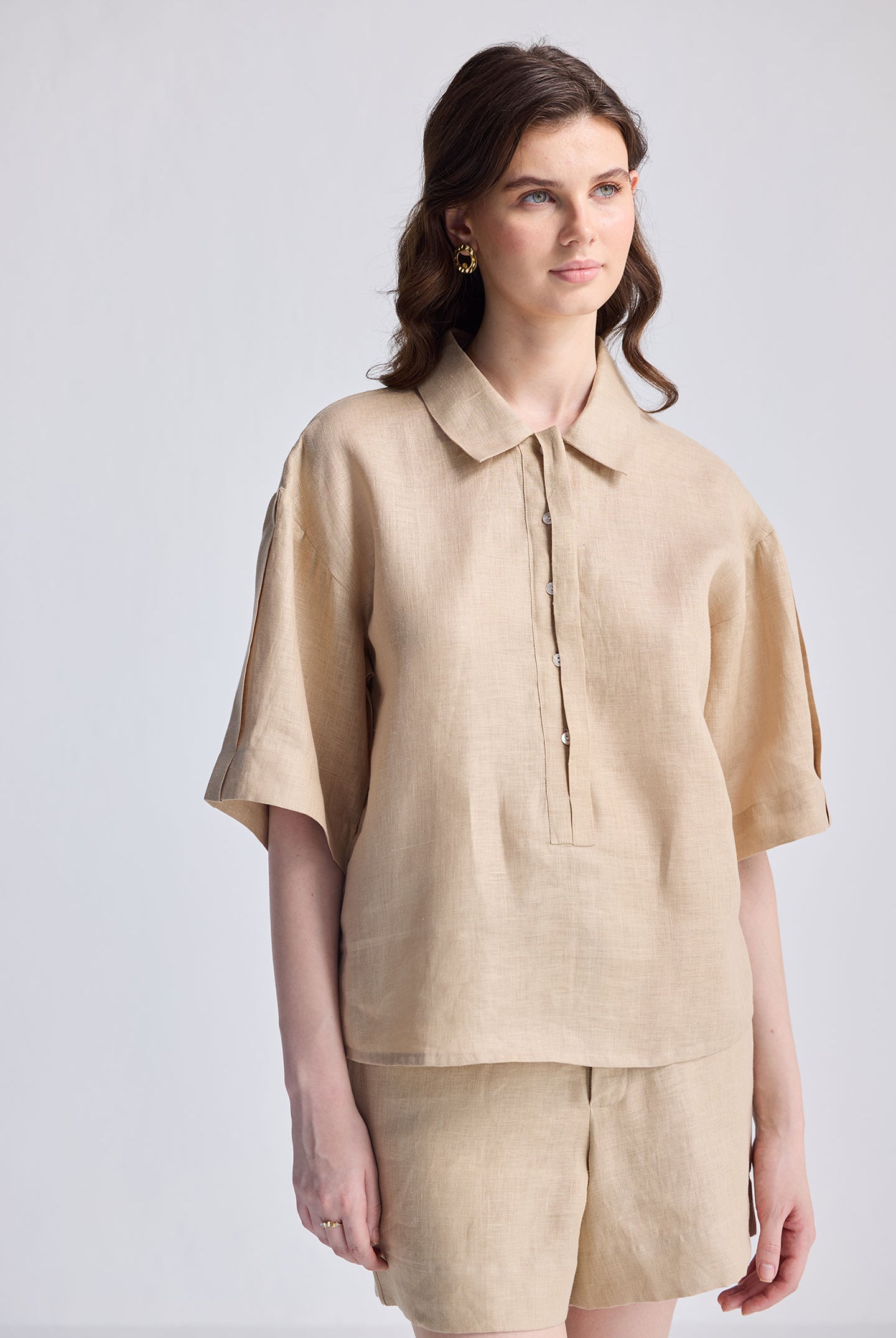 Woman wearing the Reistor Oversized Flowy Shirt in Neutral Beige, a lightweight linen-texture button-up with short sleeves and a relaxed fit, styled with matching pants.