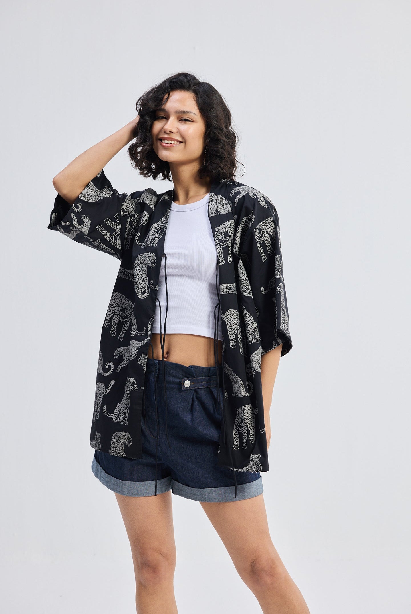 Woman wearing Oversized Shirt with Front-ties in Animal Print by reistor, styled casually on a white background.