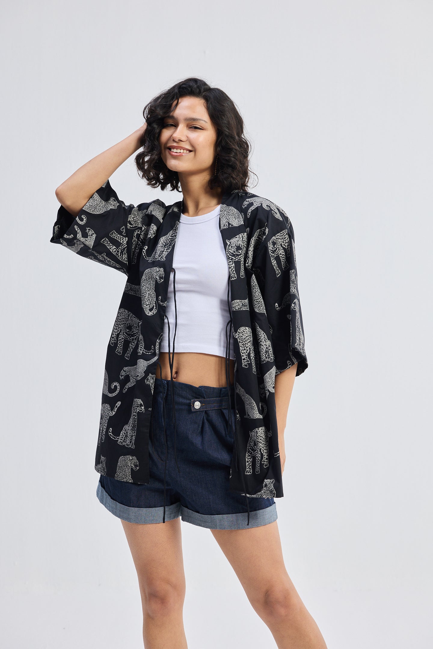 Woman wearing Oversized Shirt with Front-ties in Animal Print by reistor, styled casually on a white background.