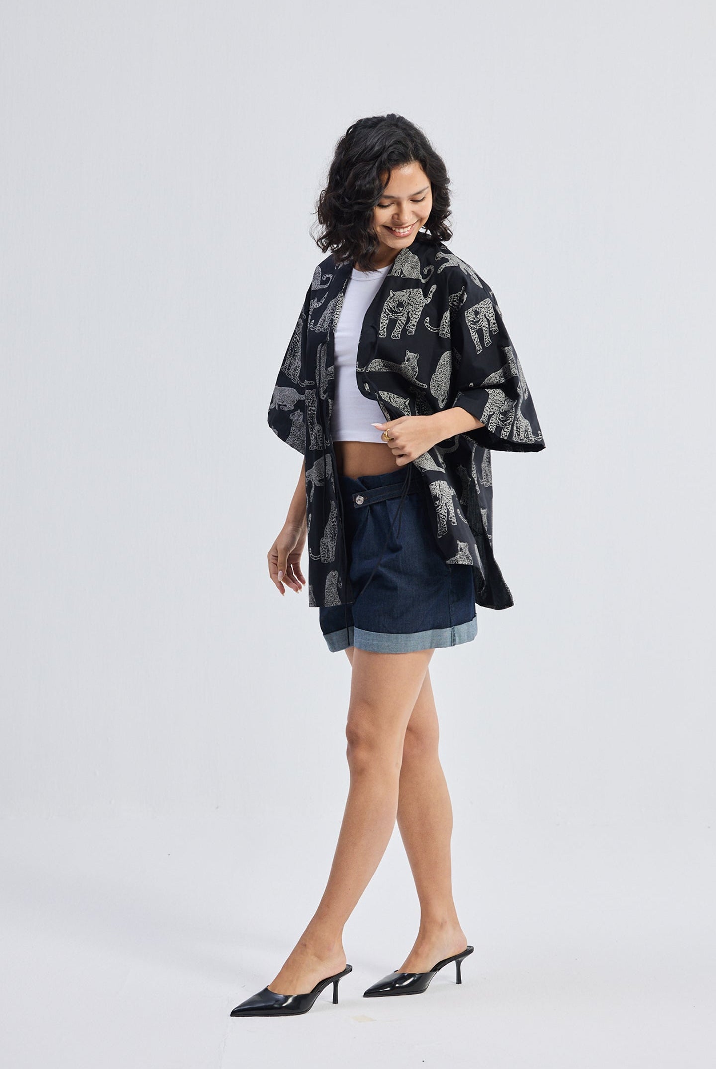 Model wearing the reistor Oversized Shirt with Front-ties in Animal Print, styled with a white crop top and denim skirt against a plain light background.