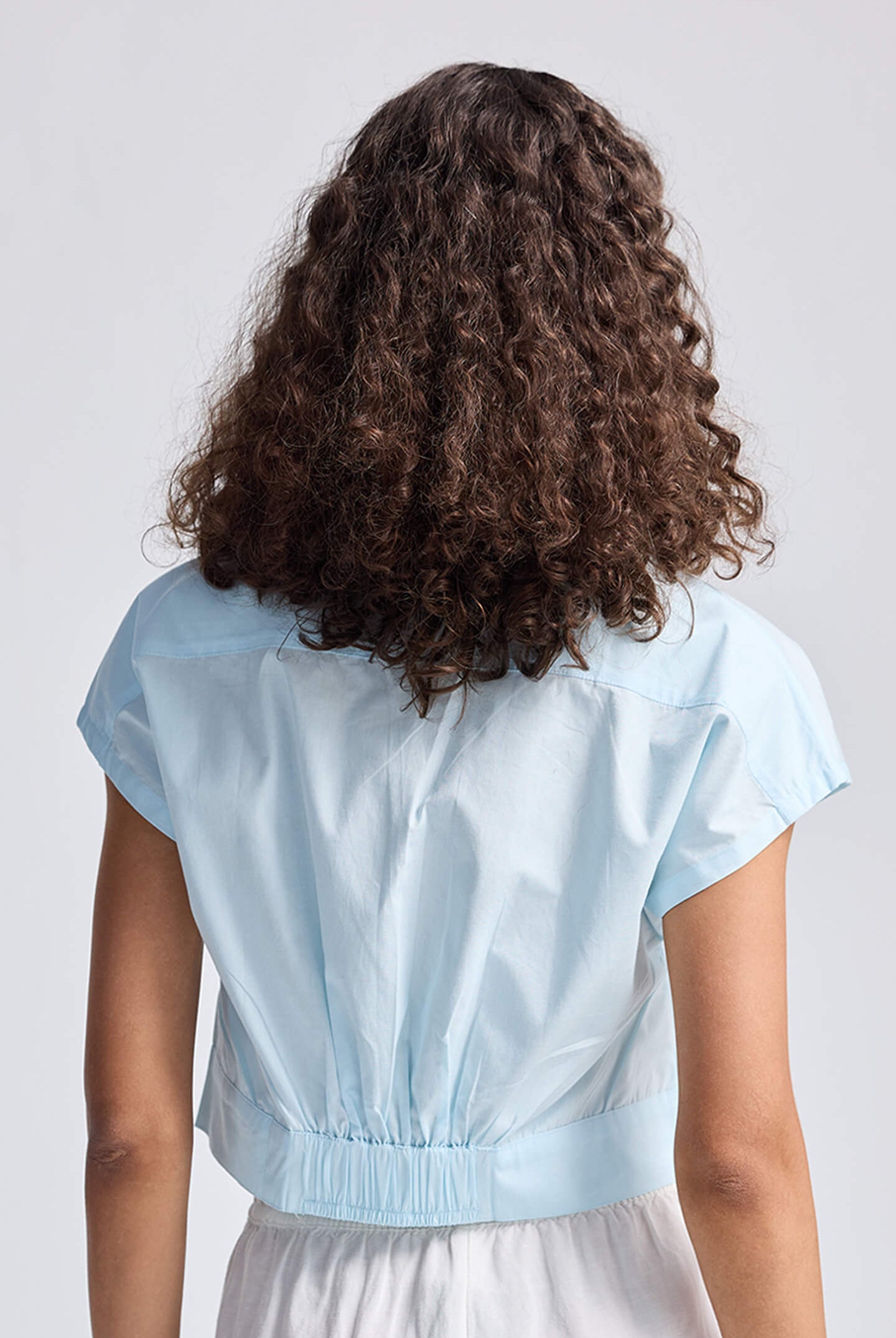 Rear view of the reistor Oversized Crop Shirt in Summer Blue showcasing the unique cinched waist design.