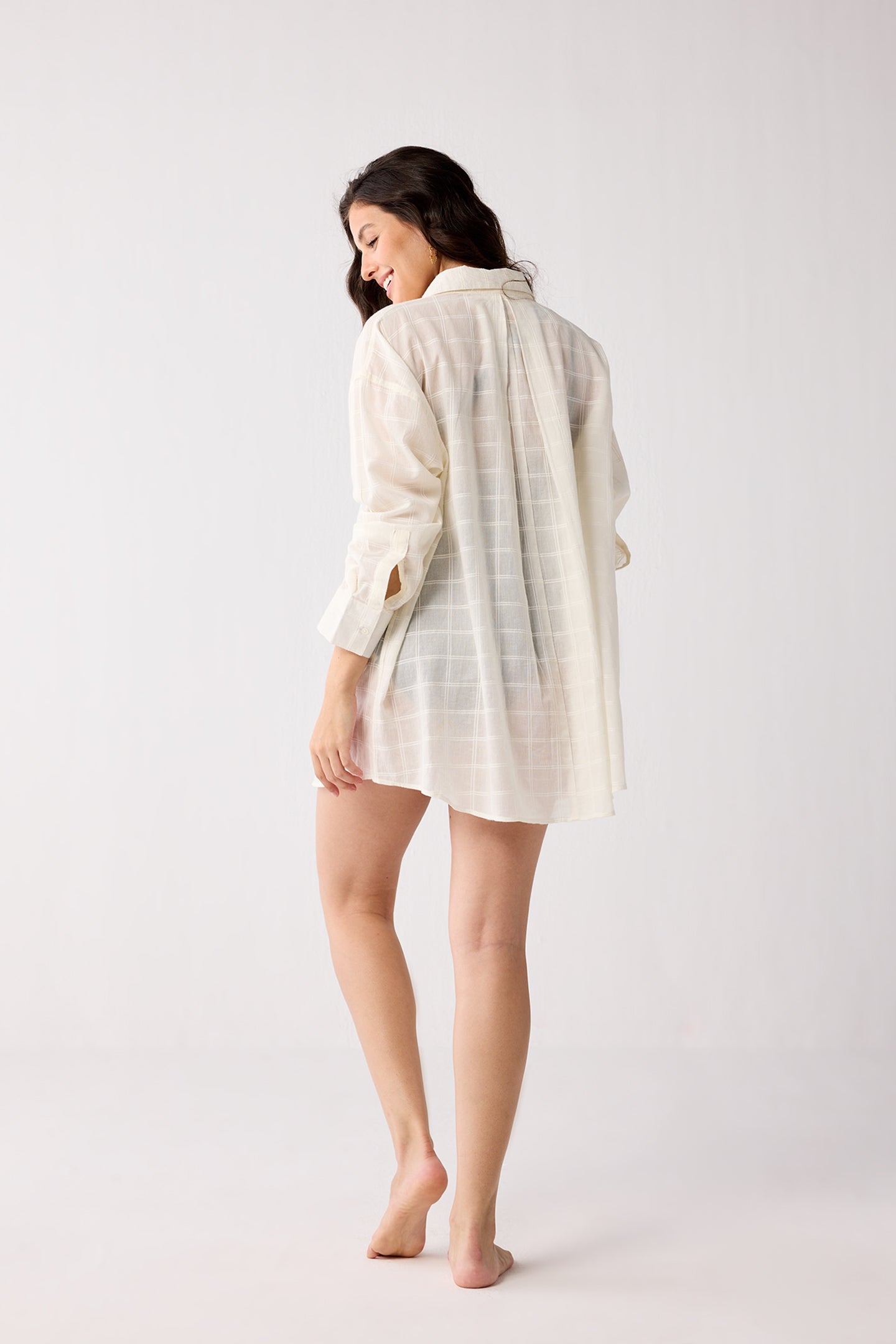 Woman wearing a white checkered shirt against a plain background