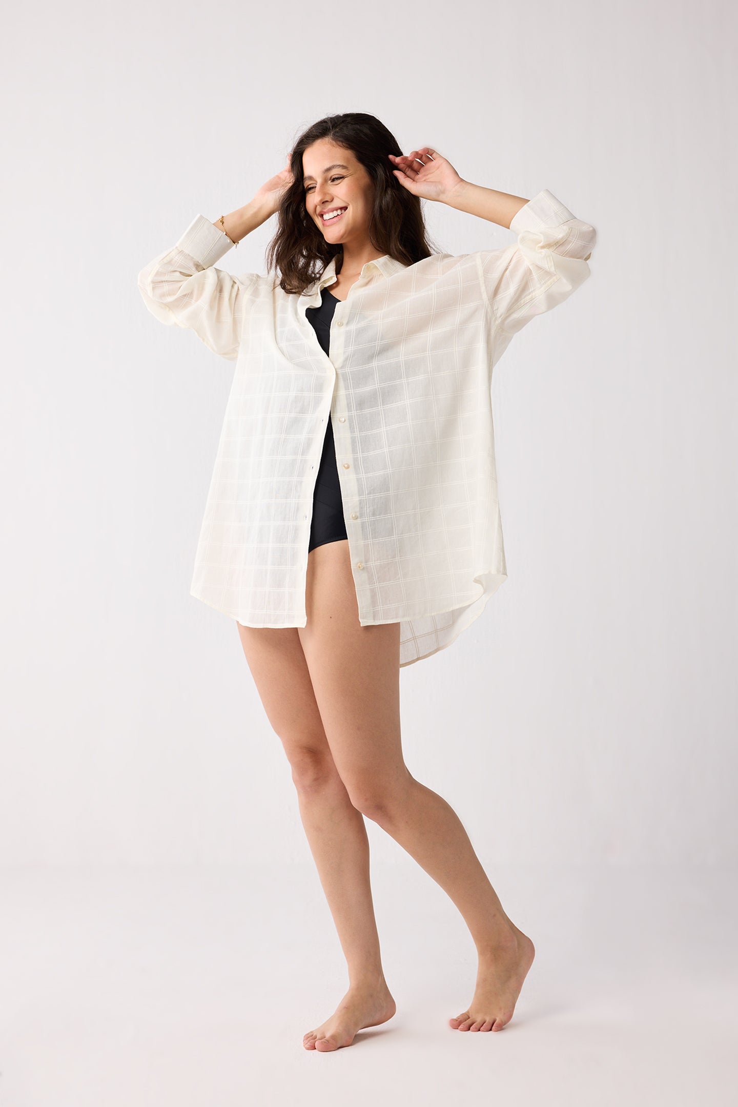 Woman wearing a white sheer jacket over a black top on a white background