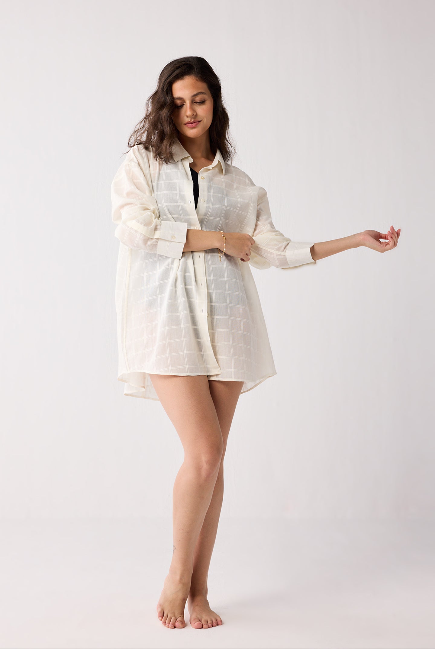 Woman wearing a light-colored checkered cover-up against a white background