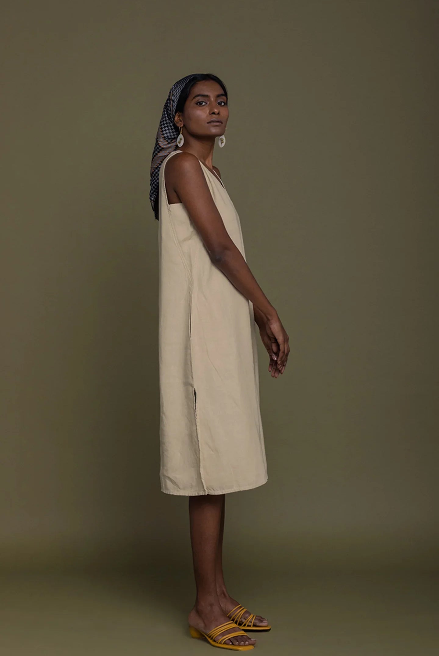 Side view of Reistor Reading Tea Leaves Dress in Neutral Beige, sleeveless V-neck midi dress for women.