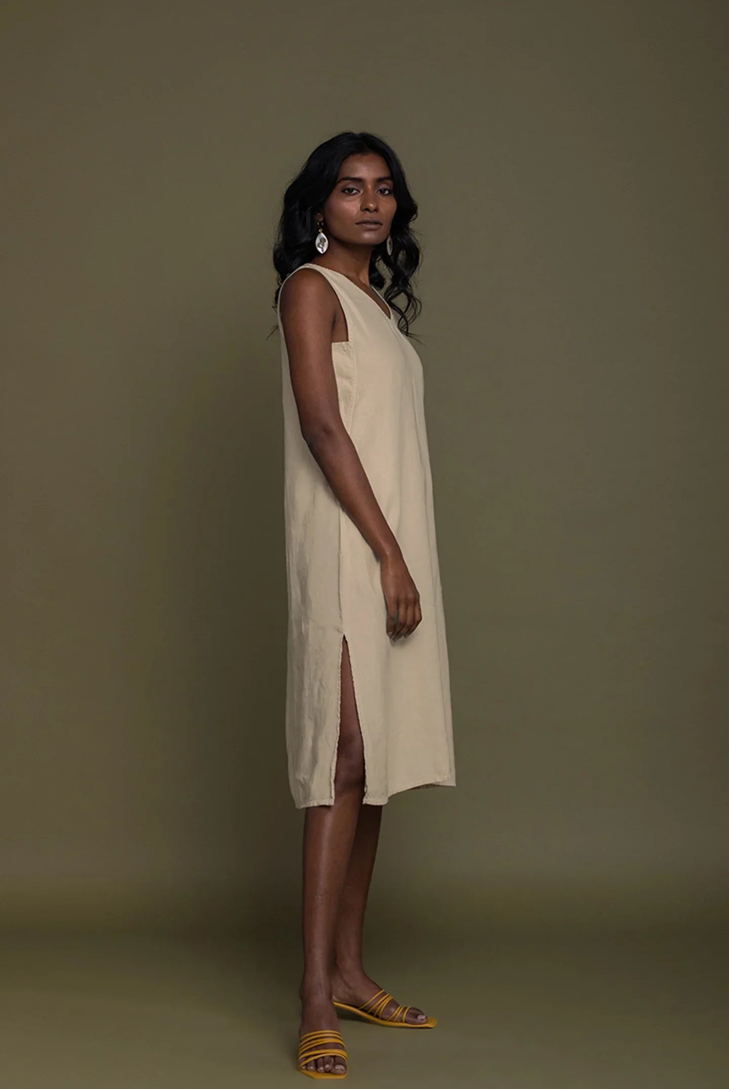 Side view of Reistor Reading Tea Leaves Dress in Neutral Beige, sleeveless V-neck midi dress with side slit.