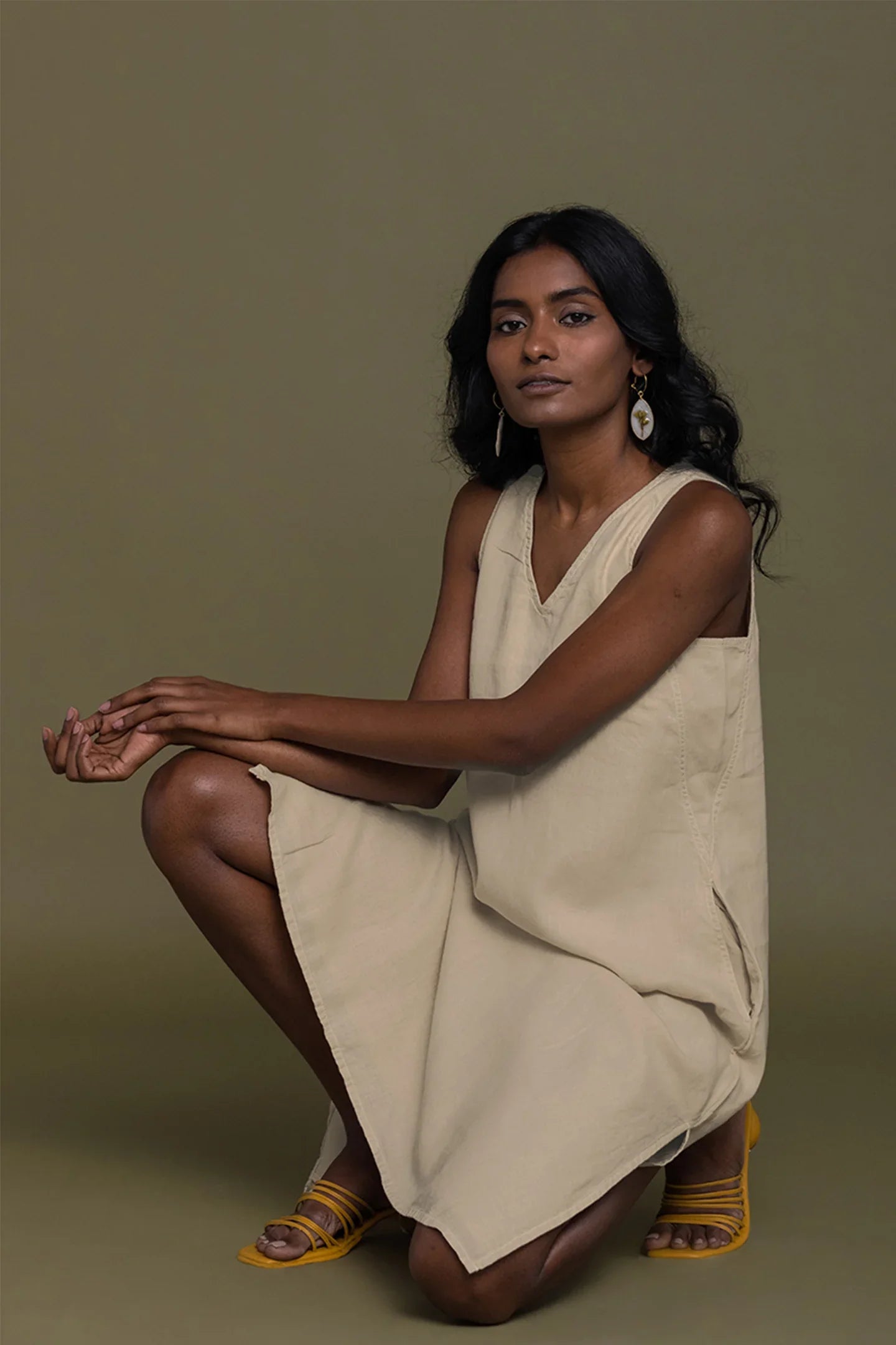 Reistor Reading Tea Leaves Dress in Neutral Beige, sleeveless V-neck midi dress shown in a seated pose.