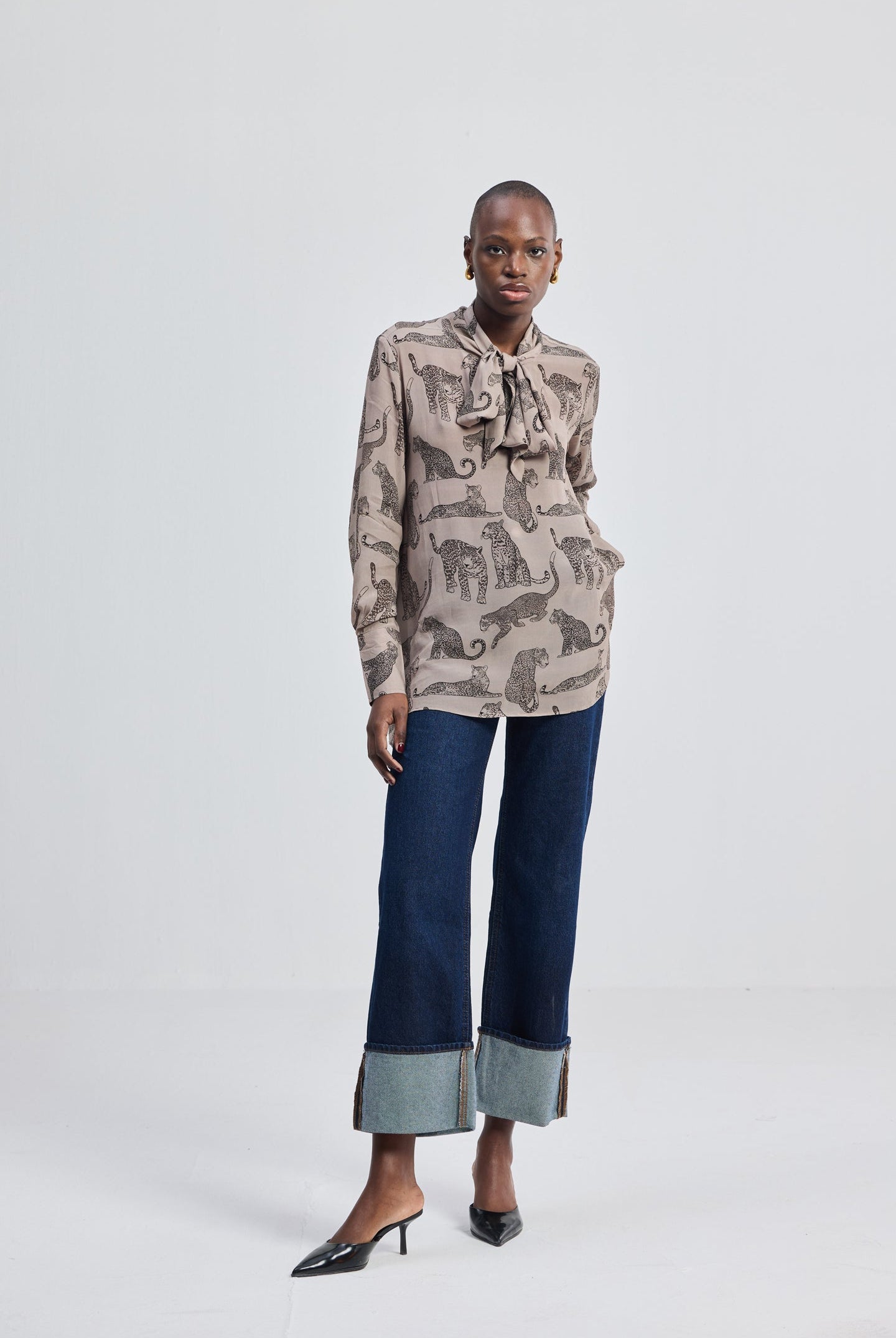 Reistor Relaxed-Fit Top with Front-tie in Animal Print, full-body front view featuring long sleeves, tie-neck detail, animal print pattern, and a relaxed fit styled with wide-leg denim and heels.