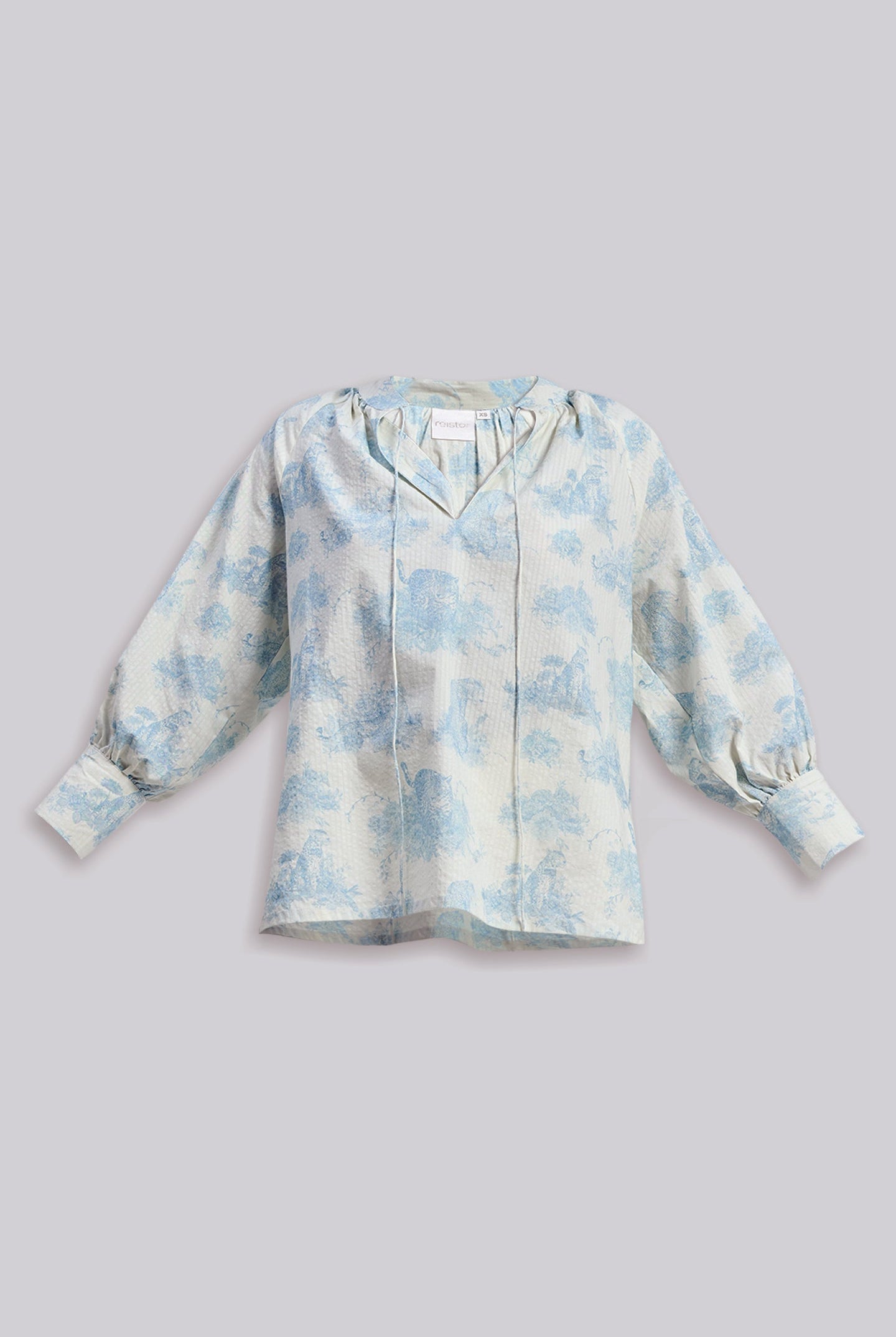Flat lay of the reistor Relaxed-fit Shirt with Drawstring in Animal Print, featuring a light blue pattern and gathered sleeves on a neutral background.