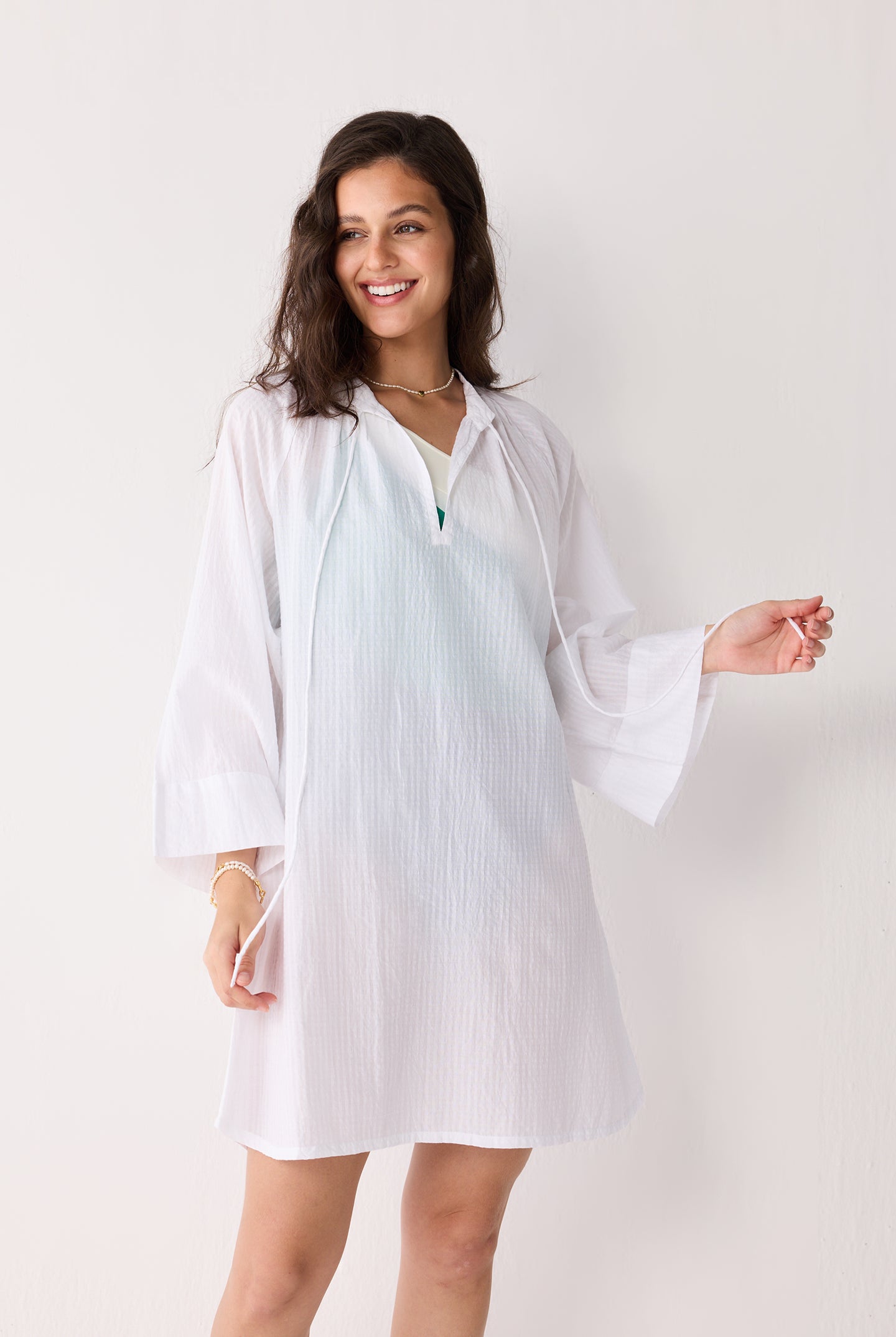 A woman wearing a white cover-up with a plain background