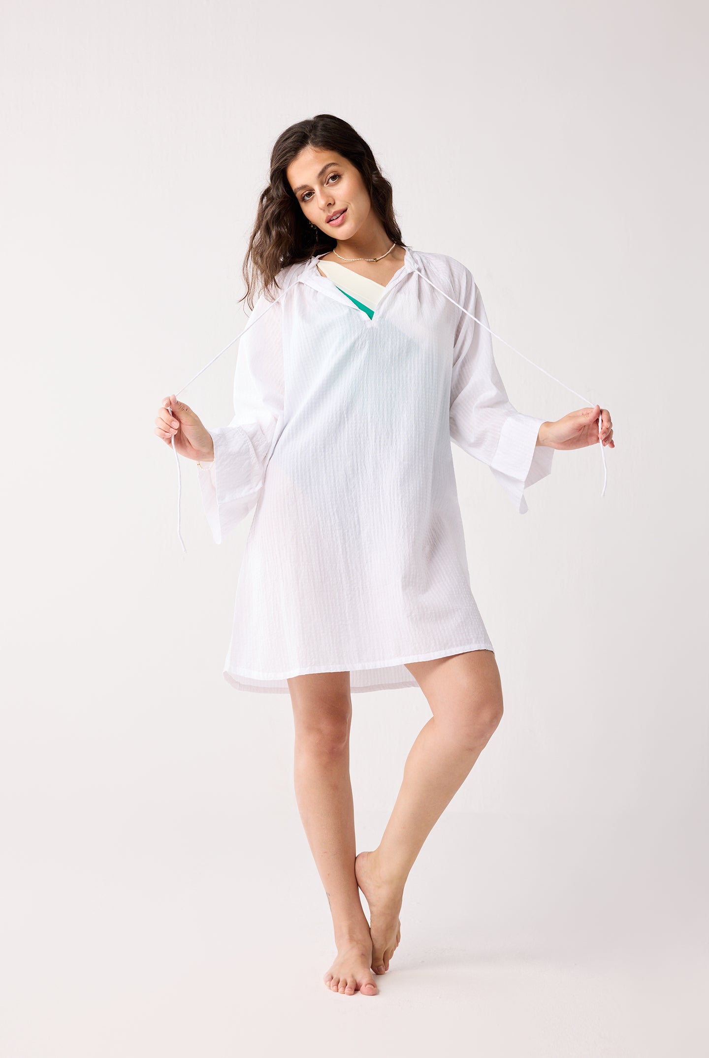 Woman wearing a white cover up on a white background