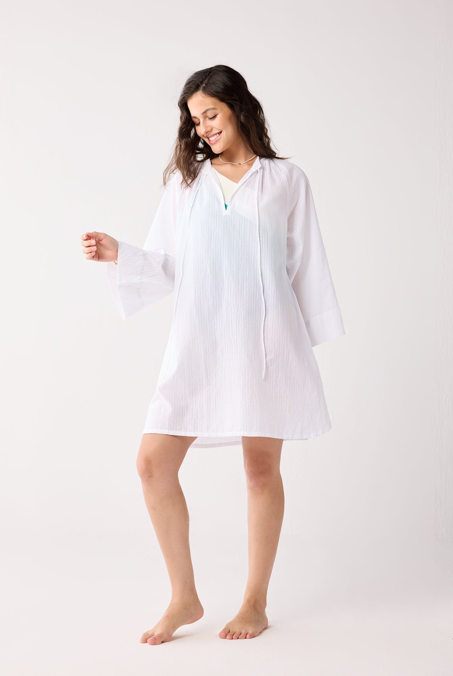 Woman wearing a white cover up on a white background