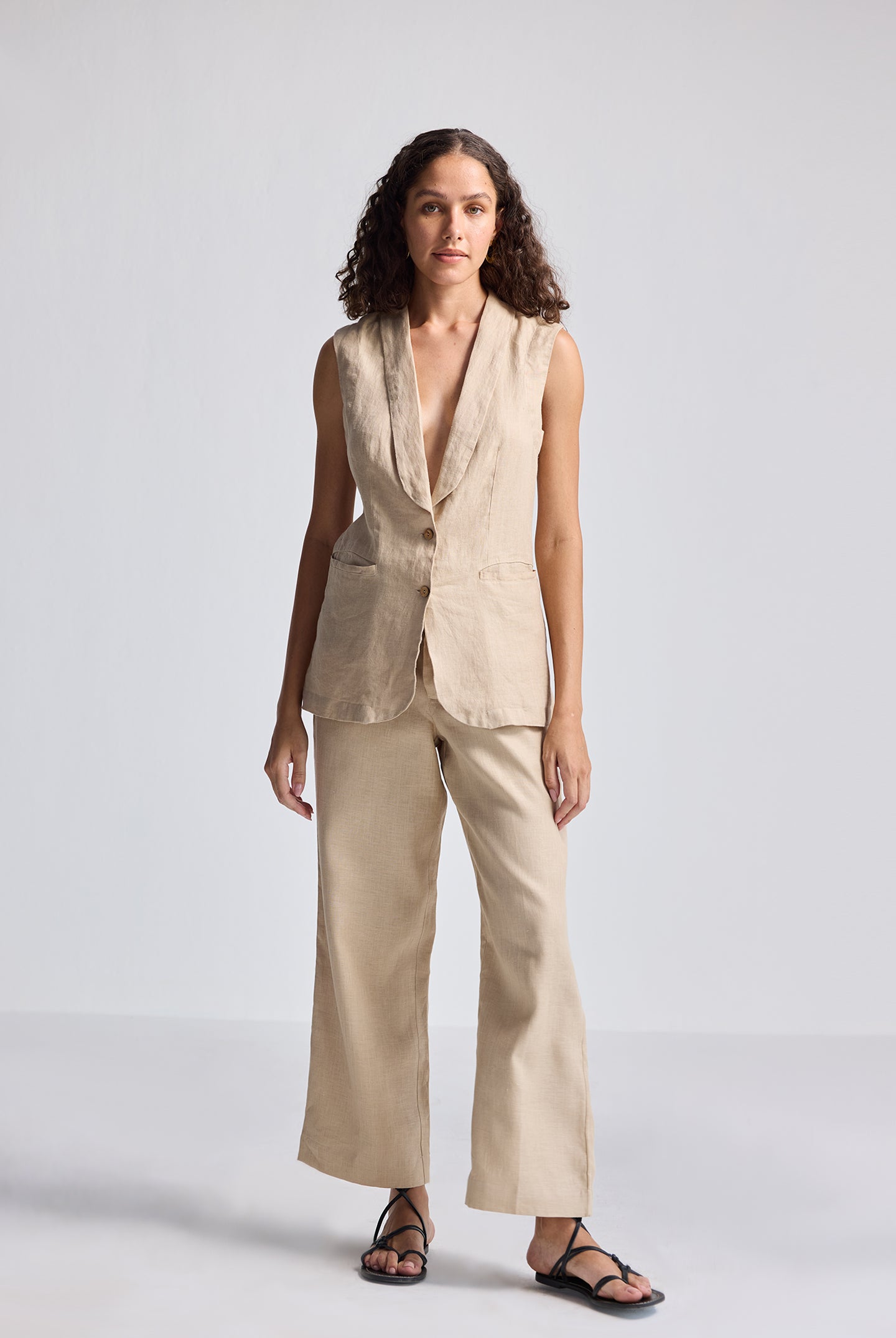 Full-length front view of model wearing Reistor Sleeveless Hemp Jacket Set in natural beige, featuring a sleeveless tailored hemp jacket paired with wide-leg hemp trousers for sustainable women’s fashion.
