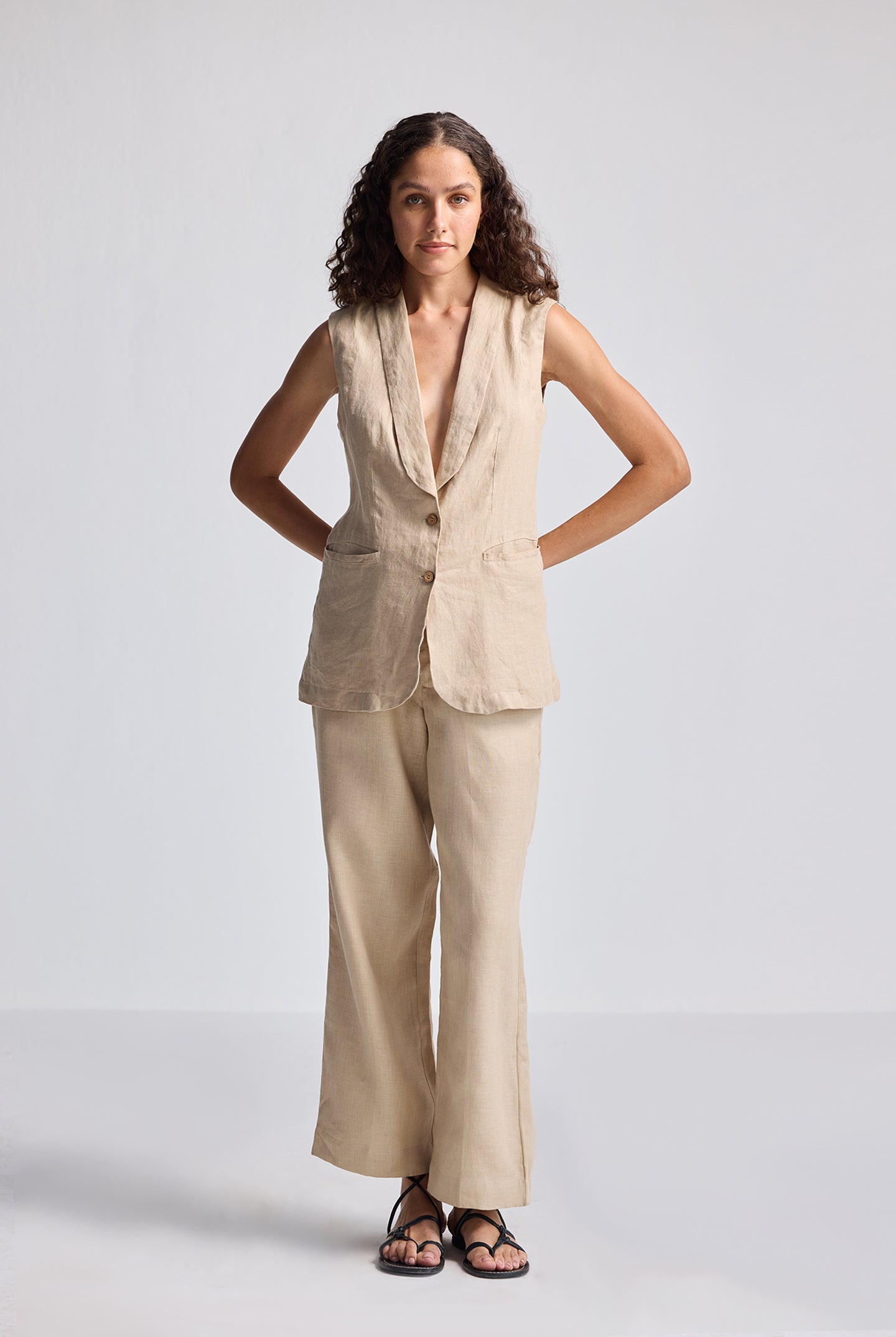 Front view of model wearing Reistor Sleeveless Hemp Jacket Set in natural beige, featuring a sleeveless hemp jacket with button detailing paired with wide-leg hemp trousers for sustainable women’s fashion.