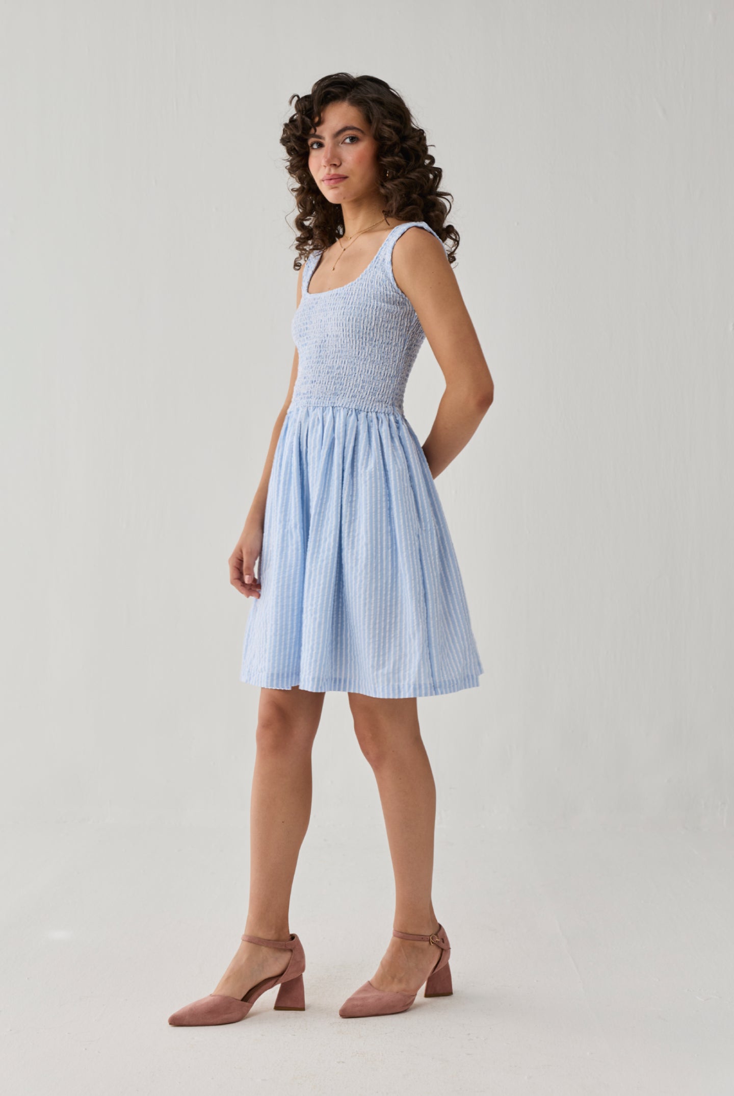 Smocked Short Dress in Blue Stripes designed with intricate smocking, a sleeveless cut, and a flowing skirt that offers comfort and charm.