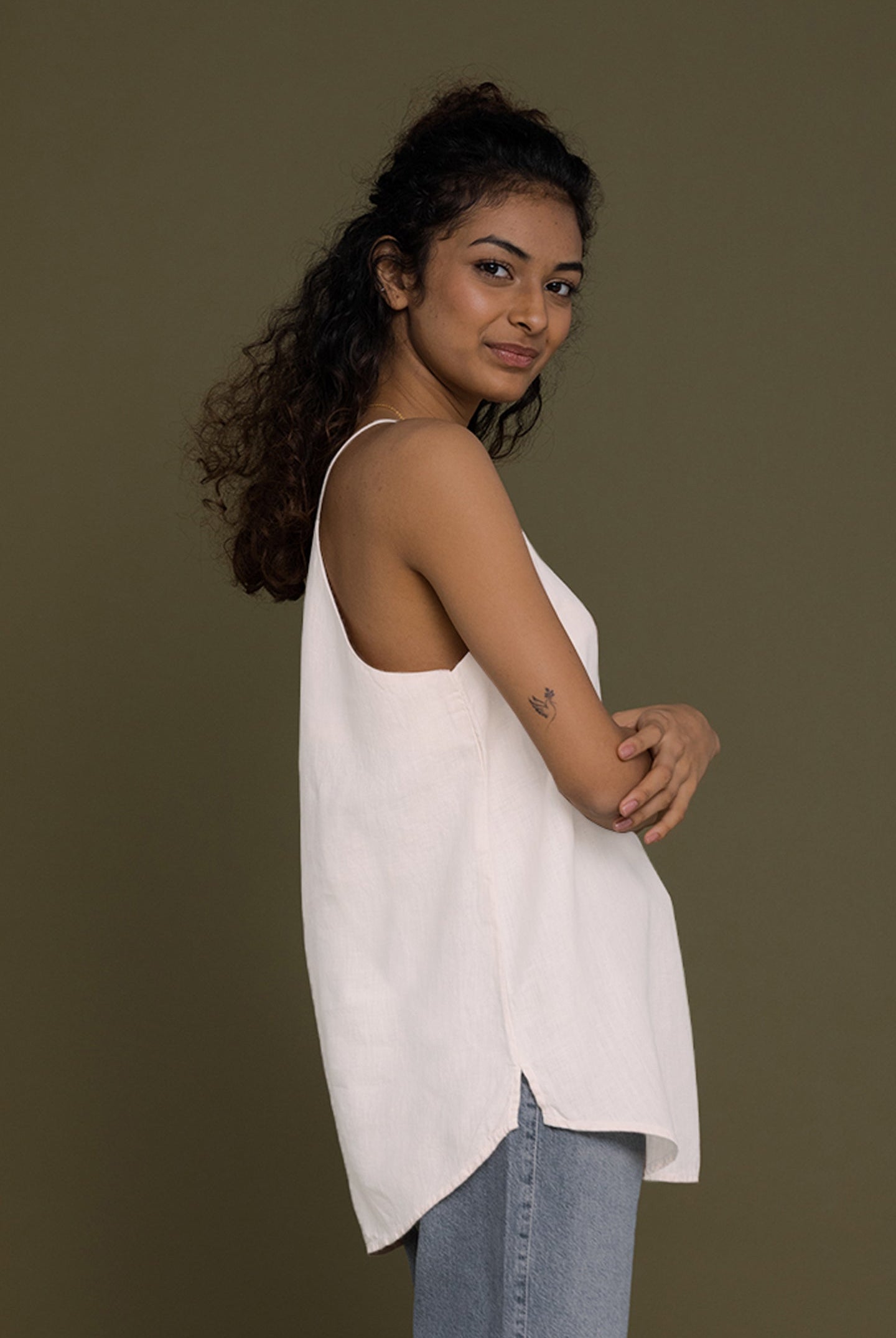 Side view of The Endless Sunday Top in White by Reistor, featuring a relaxed sleeveless silhouette, breathable fabric, curved hem, and effortless everyday style.