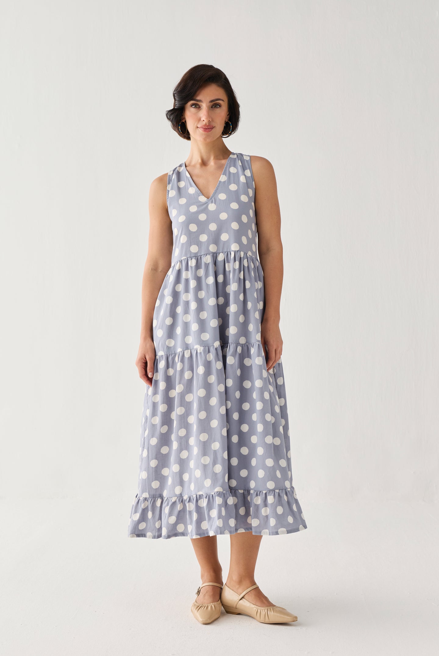 Tiered Midi Dress in Blue Polka featuring a structured V-neck bodice, softly gathered tiers, and a balanced silhouette, presented in a centered full-length view.