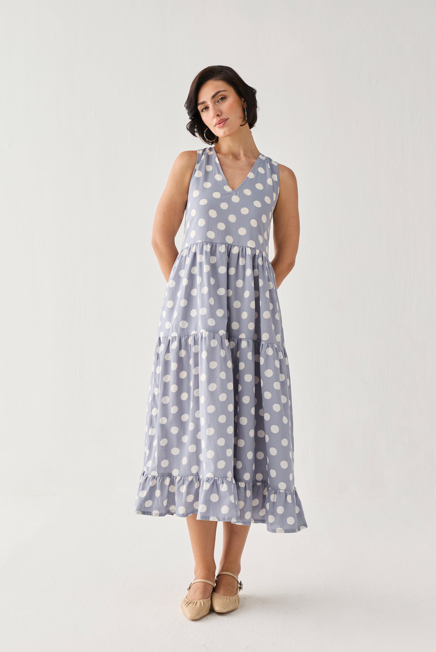 Tiered Midi Dress in Blue Polka with a relaxed empire-waist silhouette, oversized white dots, and a softly ruffled hem, styled in a graceful head-tilt pose.