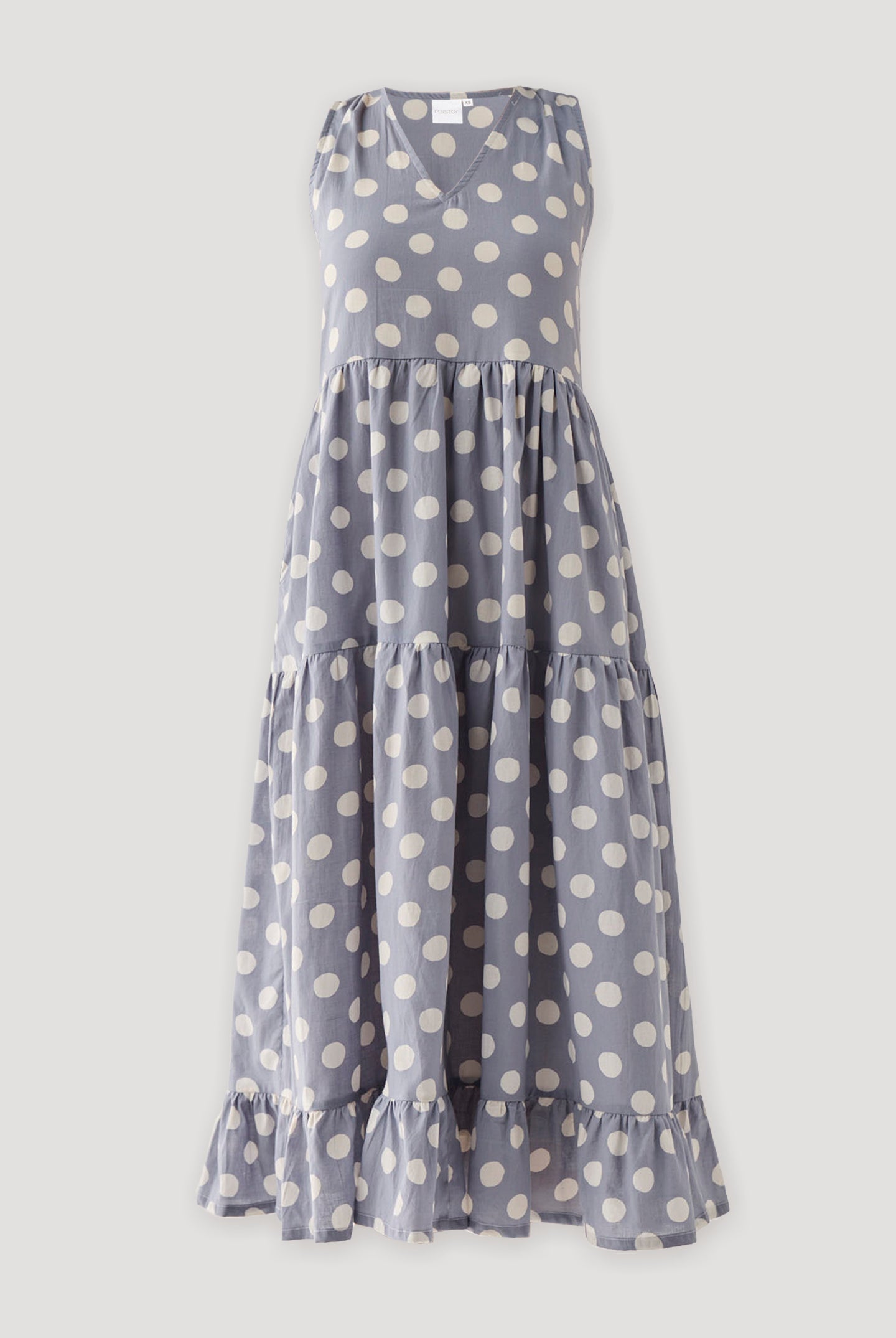 Sleeveless tiered midi dress in soft dusty blue featuring bold white polka dots, gathered layers, and a relaxed fit with elegant movement.
