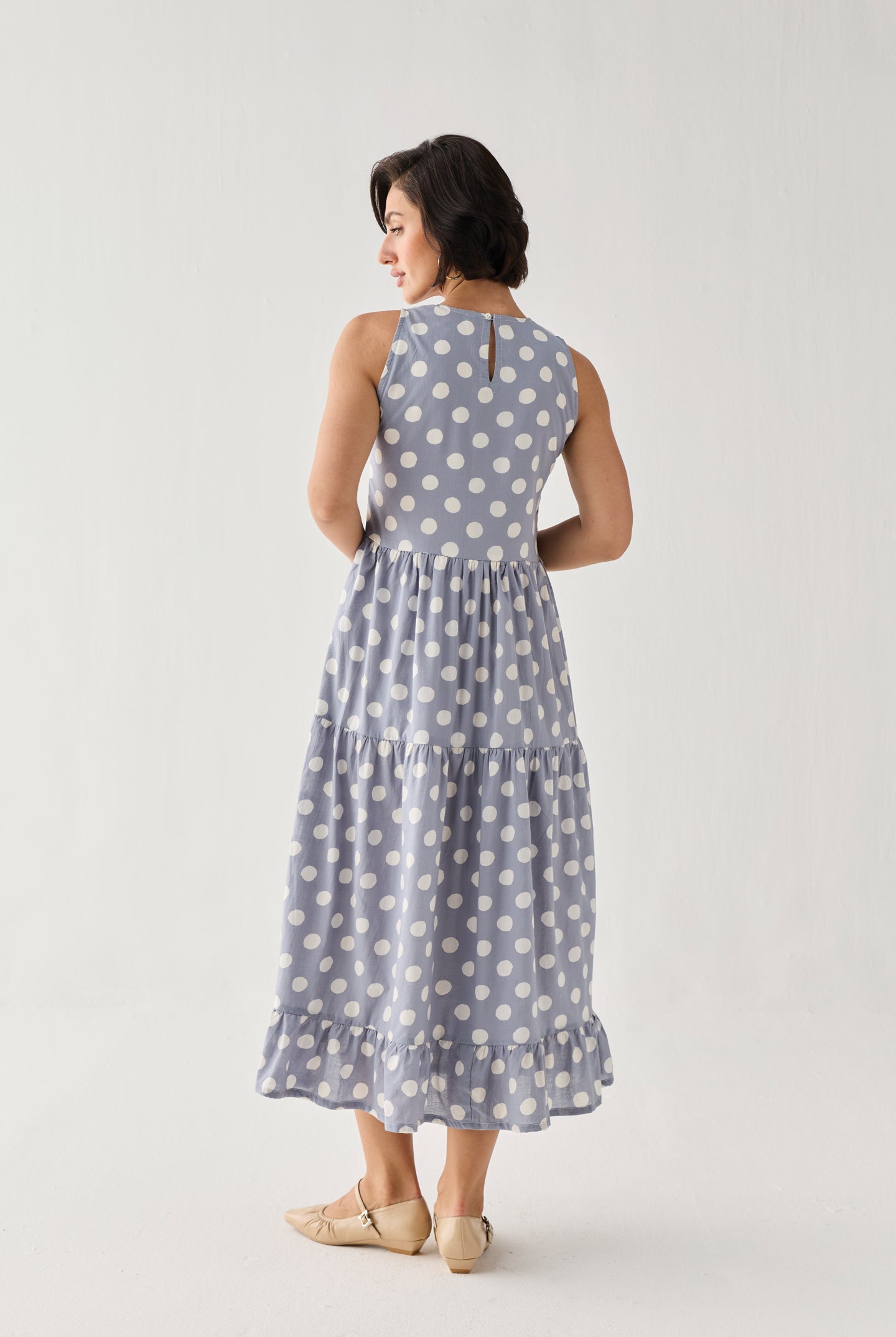 Tiered Midi Dress in Blue Polka featuring a sleeveless silhouette, white polka dot print, and flowing tiered skirt, shown from the back in a studio view.