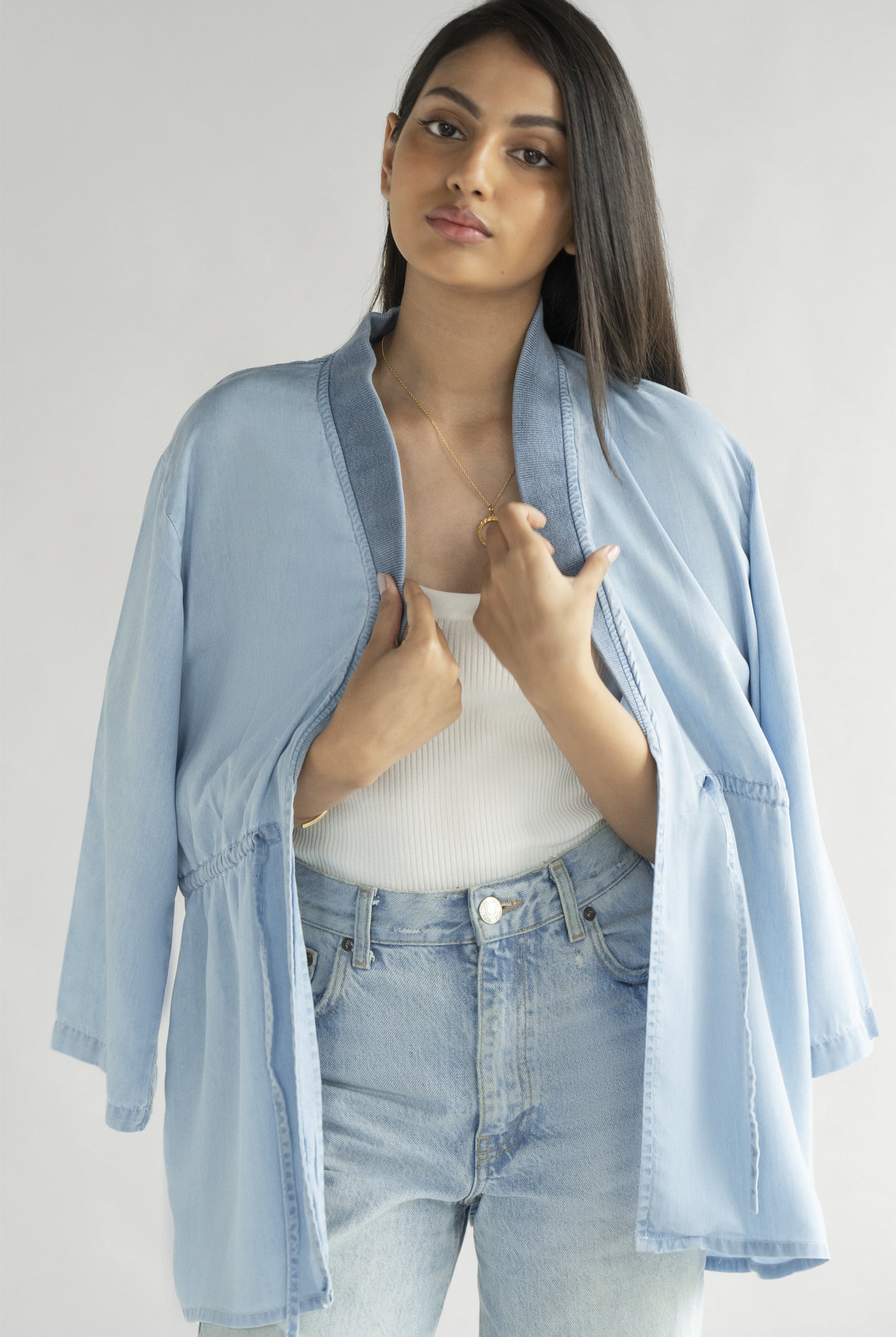 Model wearing the Reistor Travel Light Denim Jacket in Ocean Blue, highlighting breathable denim fabric, an open-front silhouette and adjustable waist detailing.