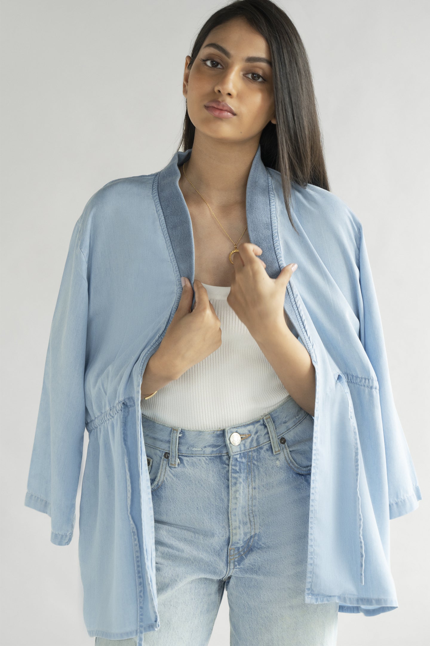 Model wearing the Reistor Travel Light Denim Jacket in Ocean Blue, highlighting breathable denim fabric, an open-front silhouette and adjustable waist detailing.