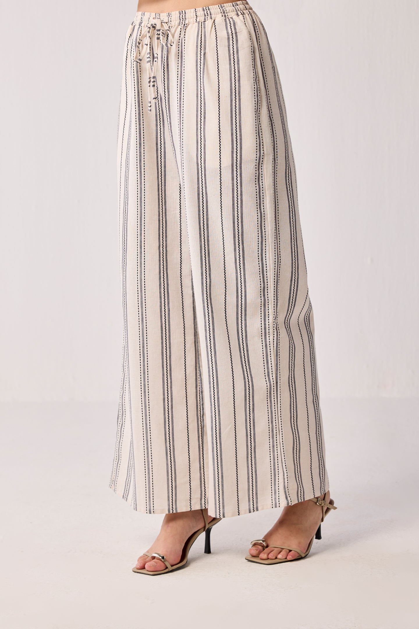 Woman wearing Wide-leg Drawstring Pants in Stripes by reistor, featuring a relaxed fit with vertical stripe detailing and a comfortable drawstring waist.