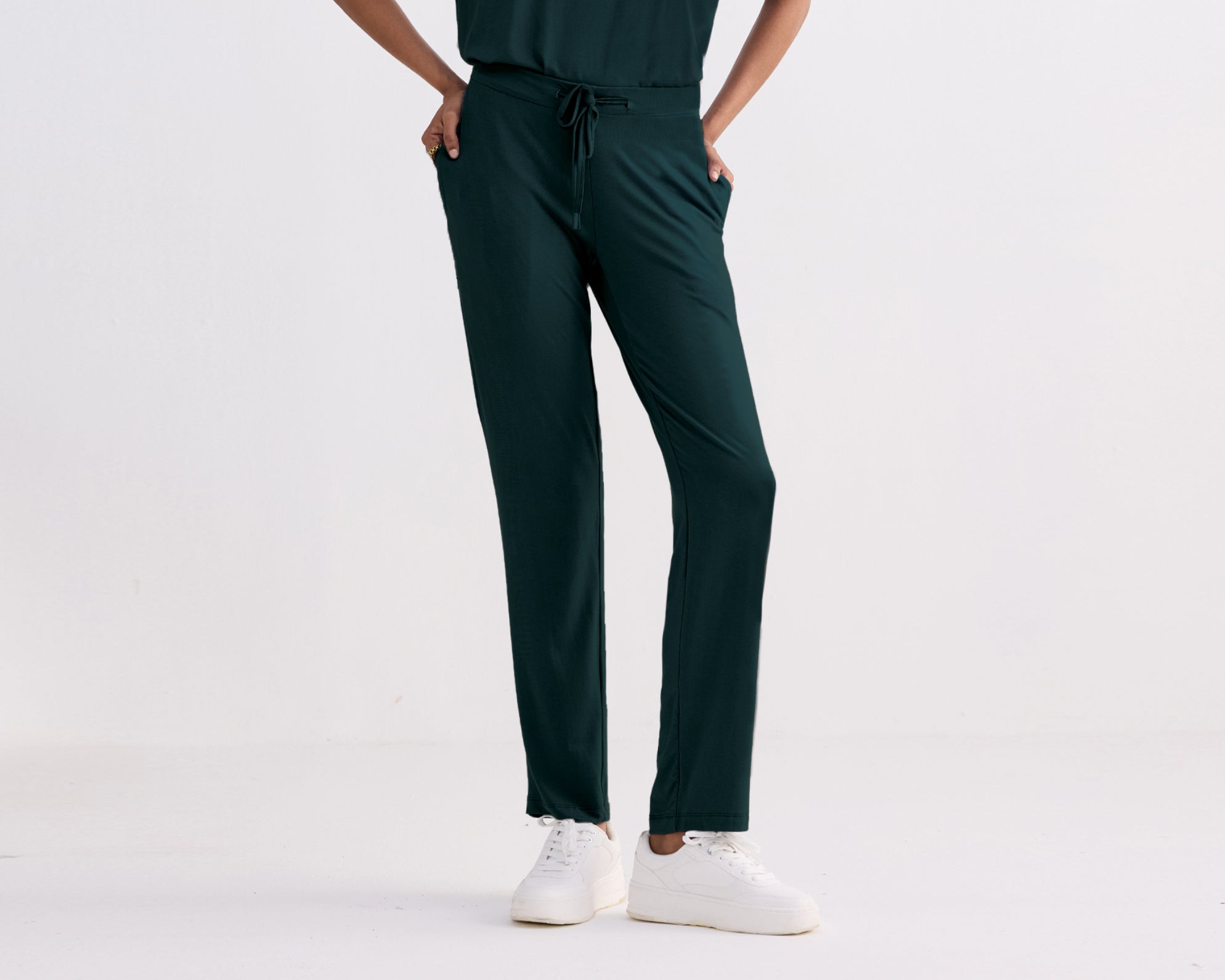 Person wearing Teal pants and white sneakers on a light gray background