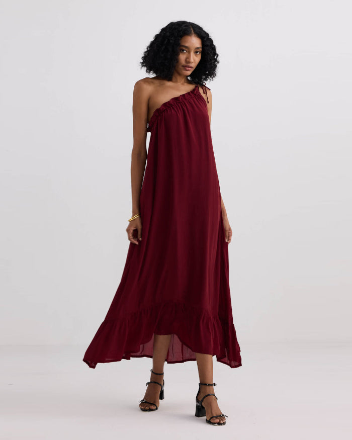 Woman wearing a burgundy one-shoulder dress on a white background