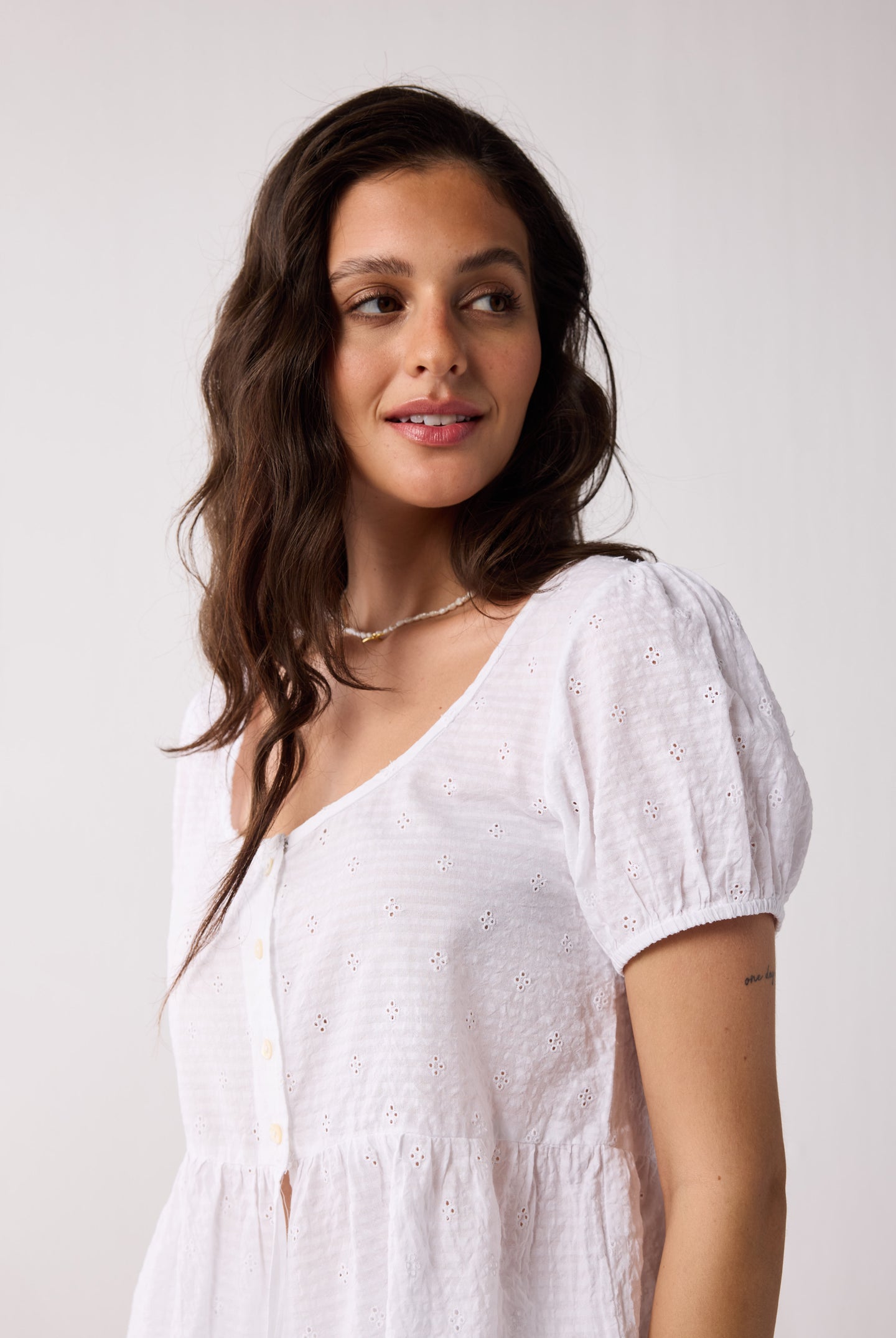 Woman wearing a white top against a plain background