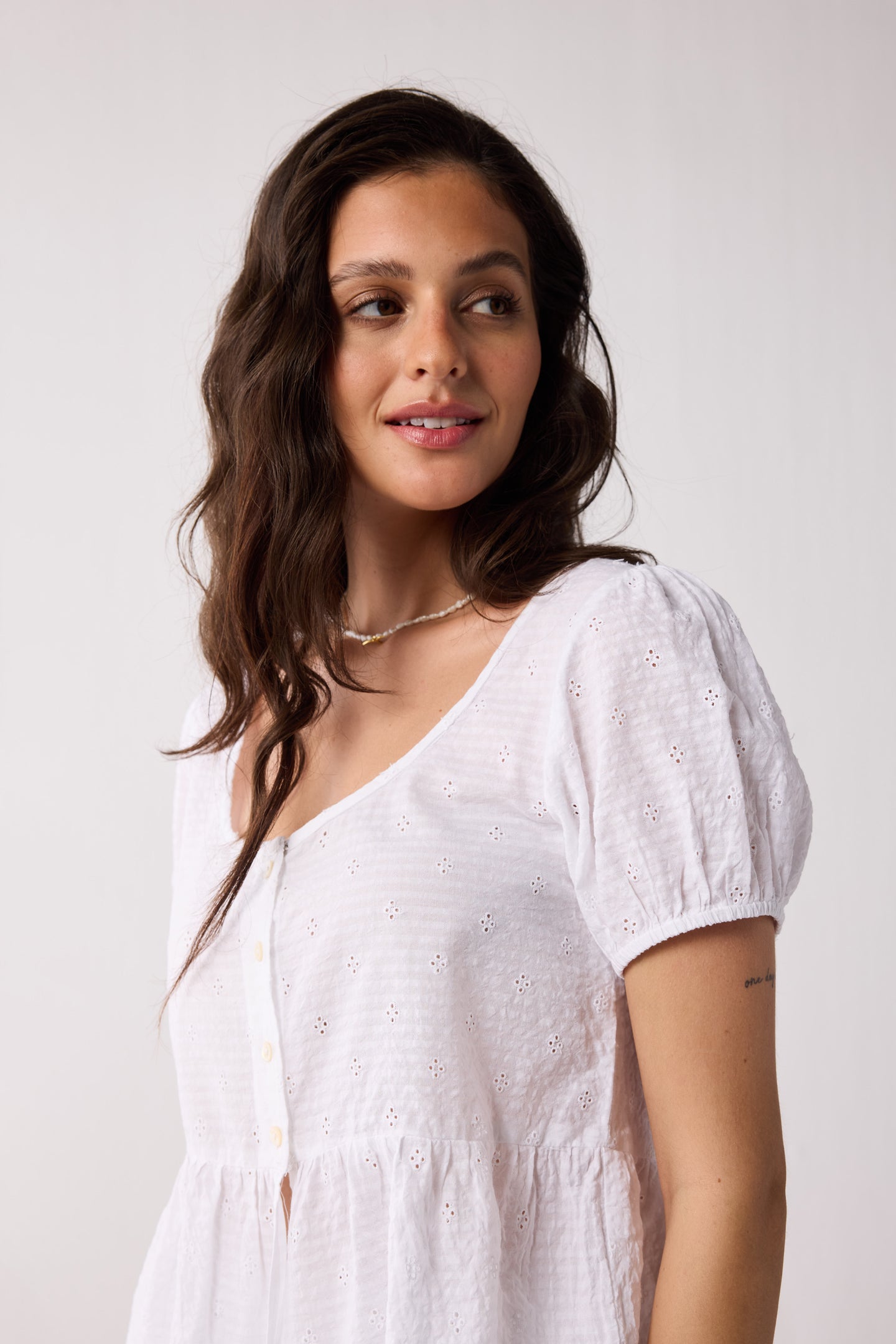 Woman wearing a white top against a plain background