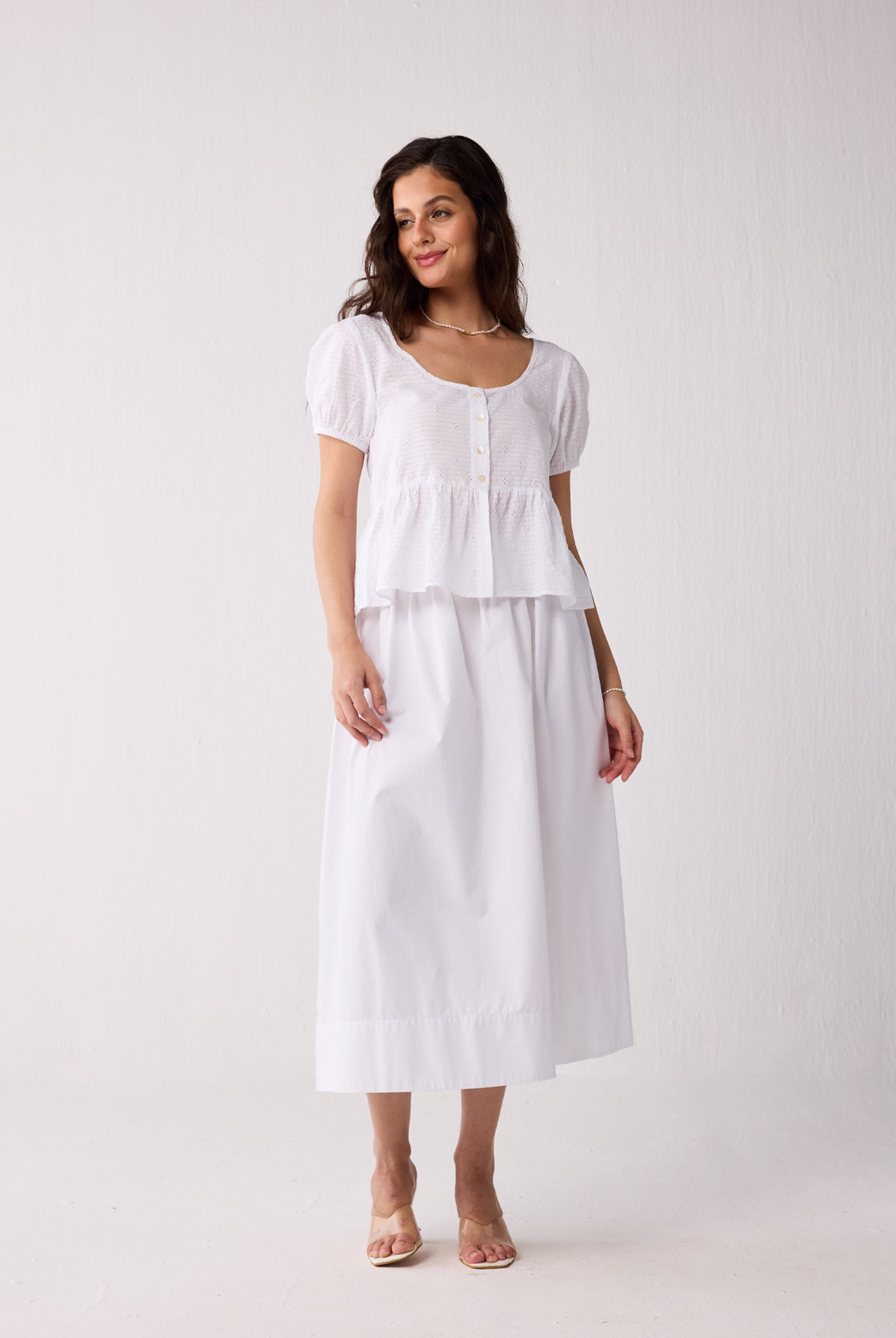 A woman wearing a white top on a plain background